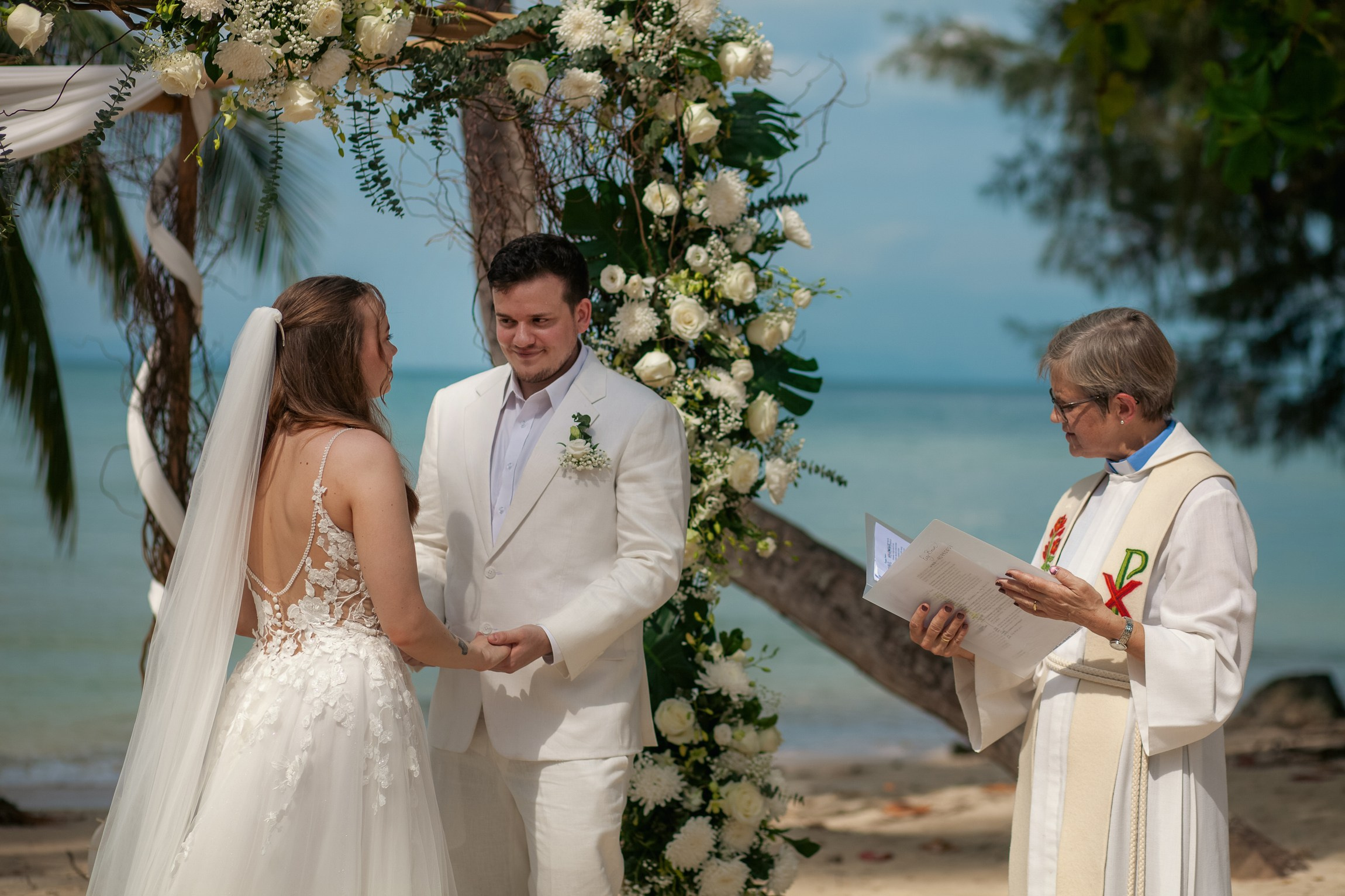 Romantic destination wedding on Koh Samui beach with tropical flowers, ocean views and happy newlyweds