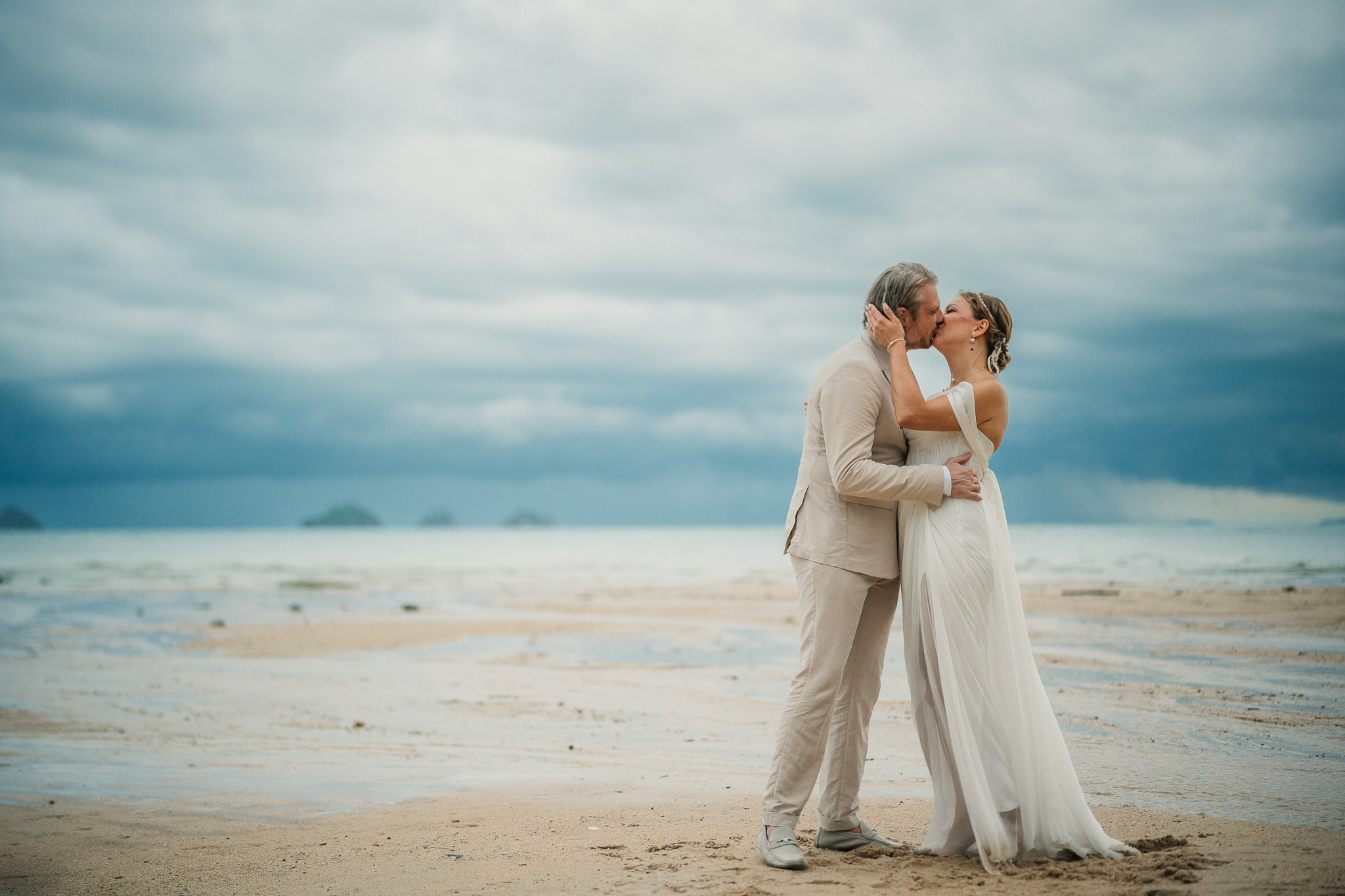 Bride and groom receiving blessings during a Buddhist wedding ceremony on the beach in Koh Samui, Thailand.