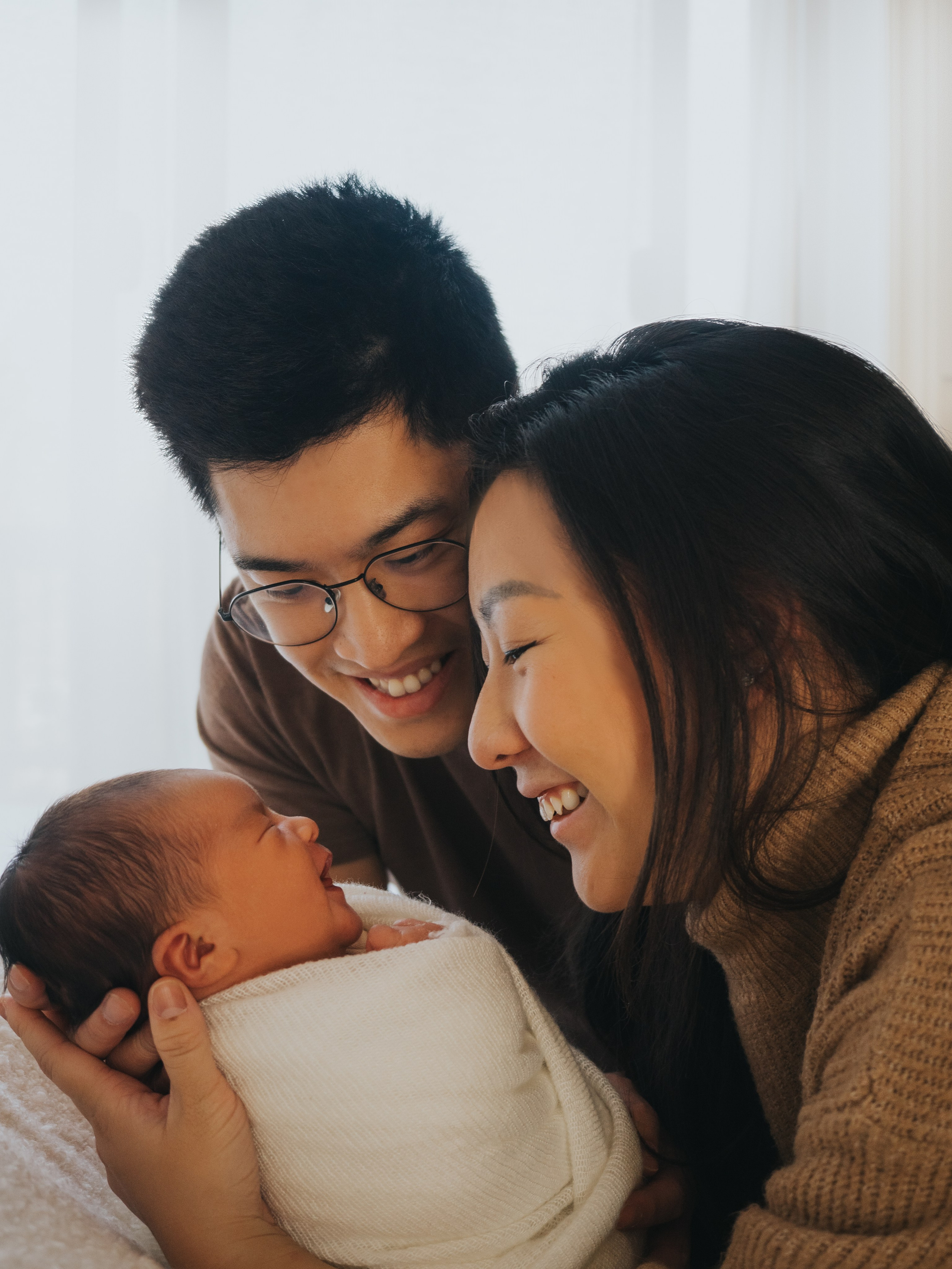 Des parents souriant à leur nouveau-né.