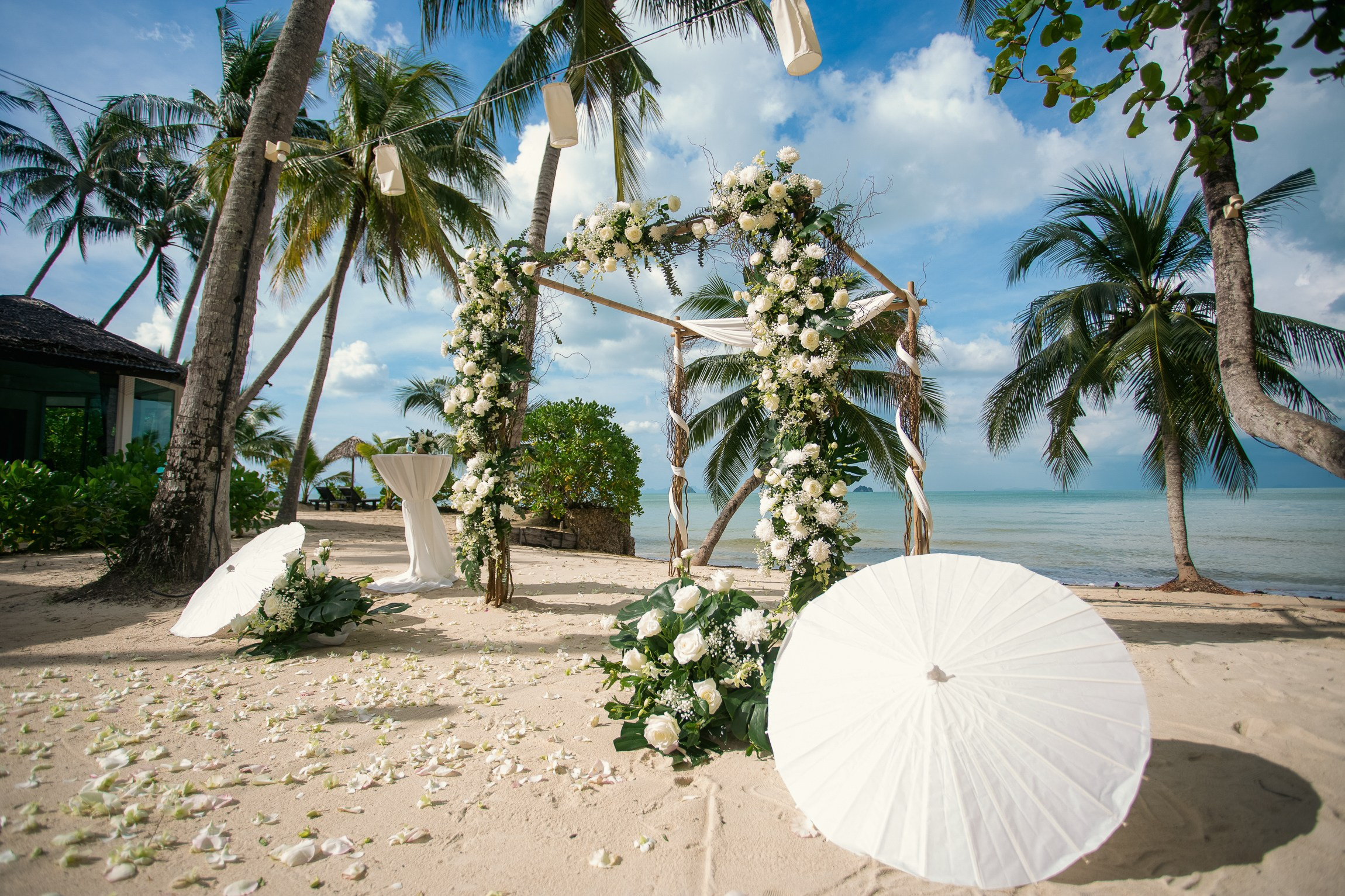 Romantic destination wedding on Koh Samui beach with tropical flowers, ocean views and happy newlyweds