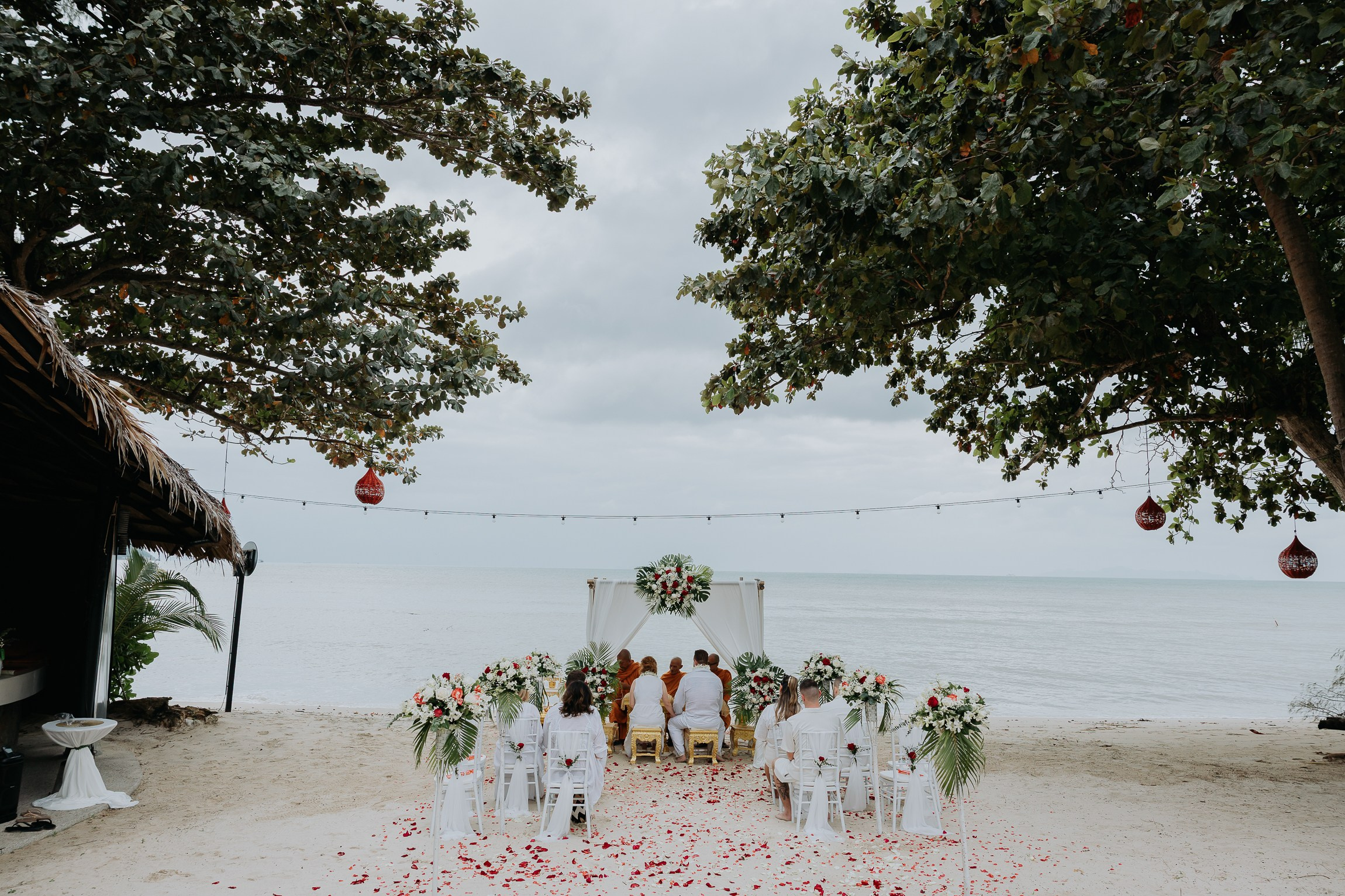 Bride and groom participating in a sacred Buddhist wedding blessing in Thailand