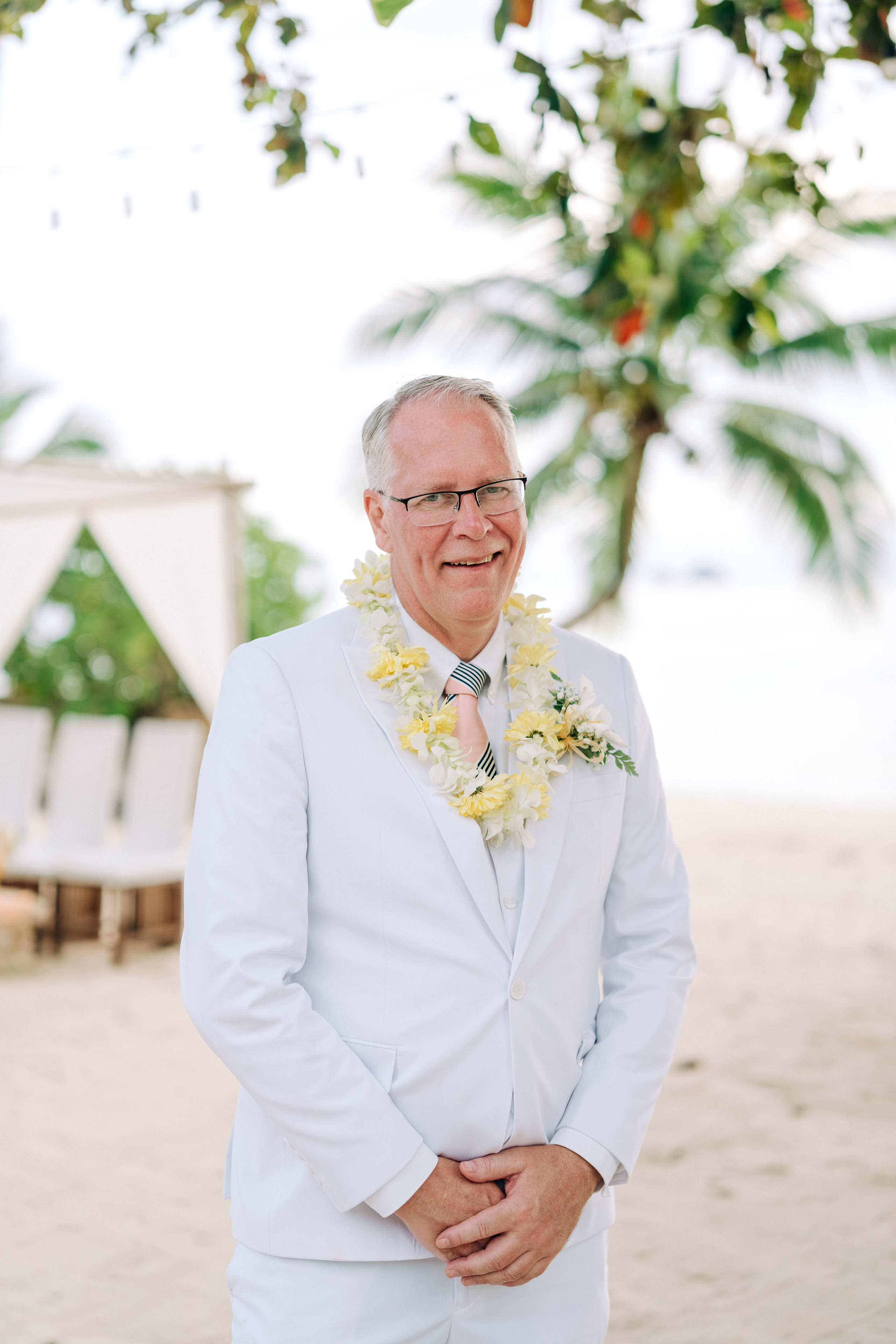 Newlywed couple celebrating a Buddhist wedding ceremony on a beautiful beach in Koh Samui, Thailand.