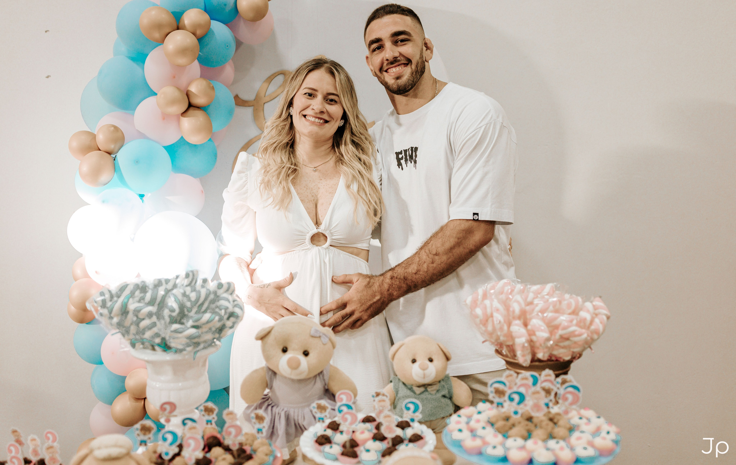 Casal na decoração do chá de bebê, sorrindo e abraçados.