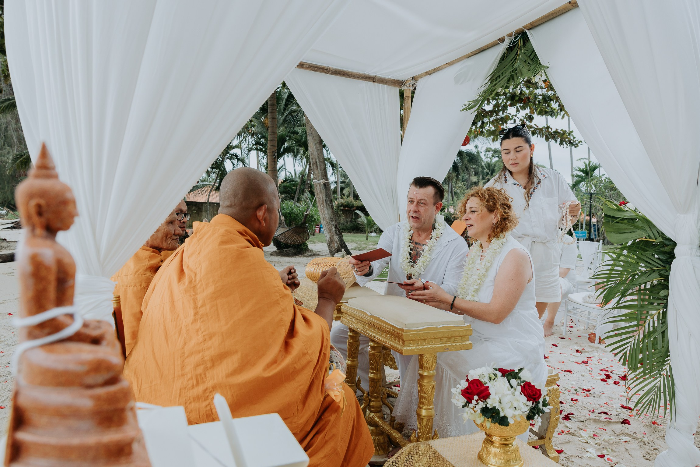 Bride and groom participating in a sacred Buddhist wedding blessing in Thailand