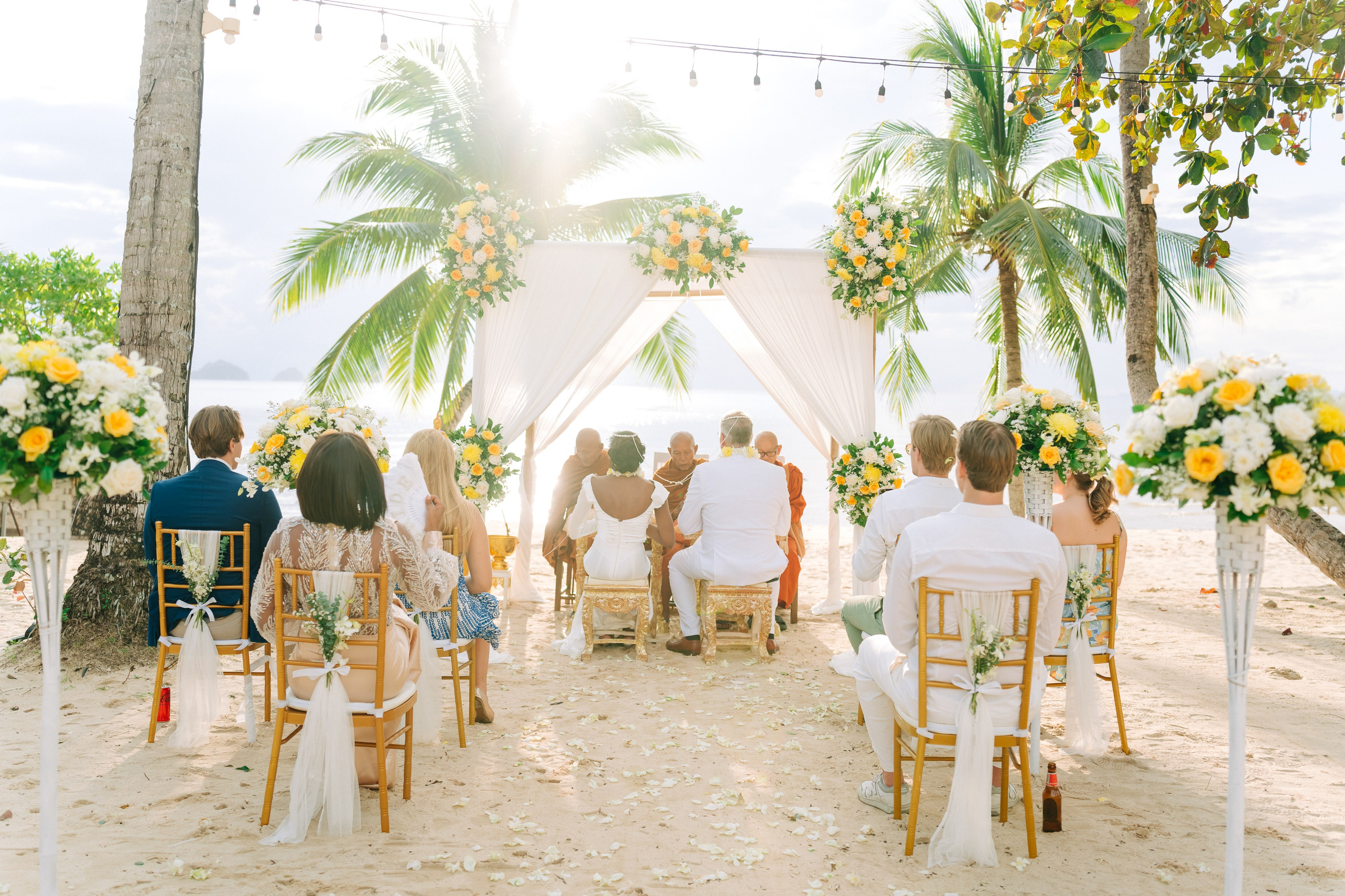 Newlywed couple celebrating a Buddhist wedding ceremony on a beautiful beach in Koh Samui, Thailand.