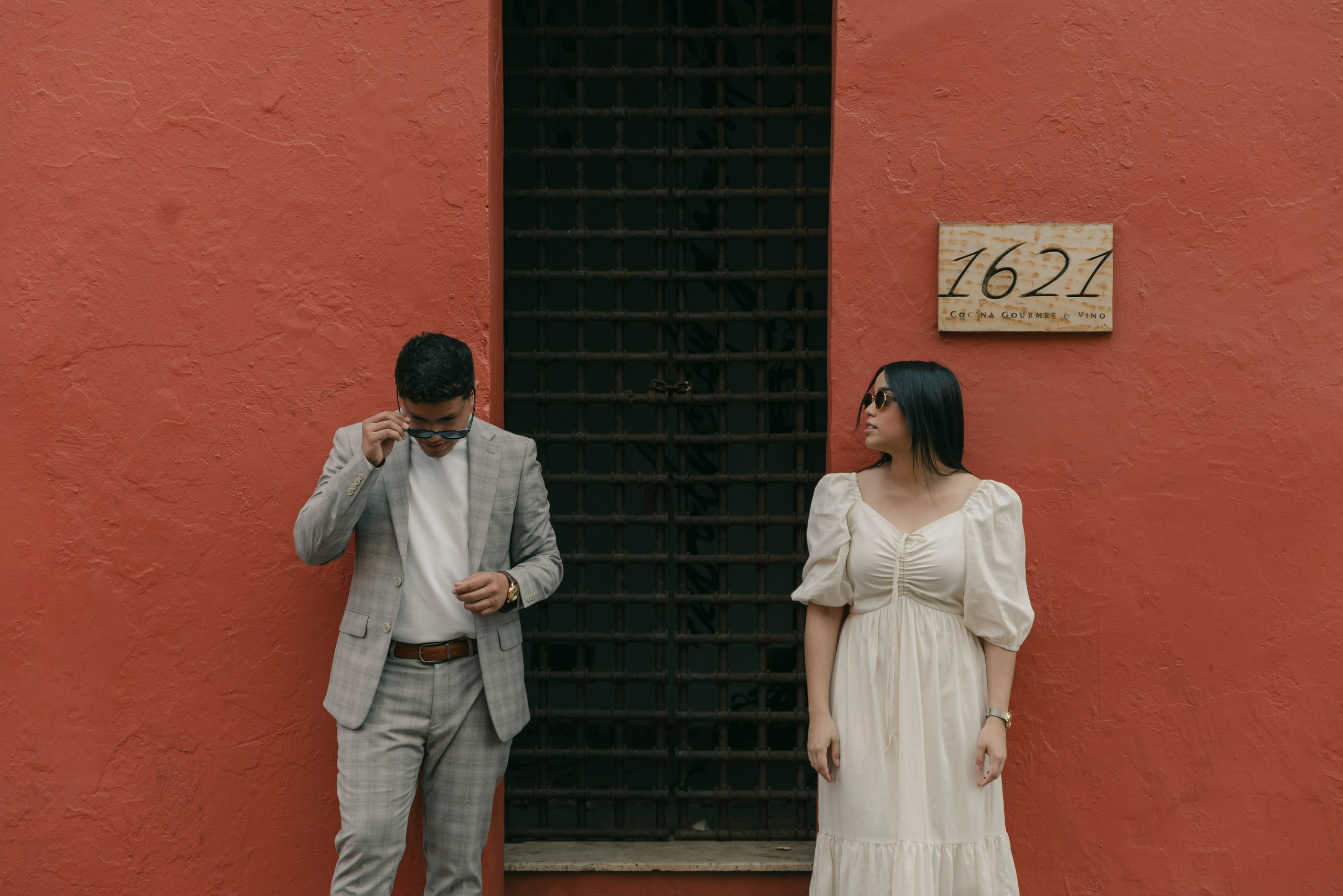 Novios frente a puerta colonial roja típica de Cartagena, sesión cinematográfica