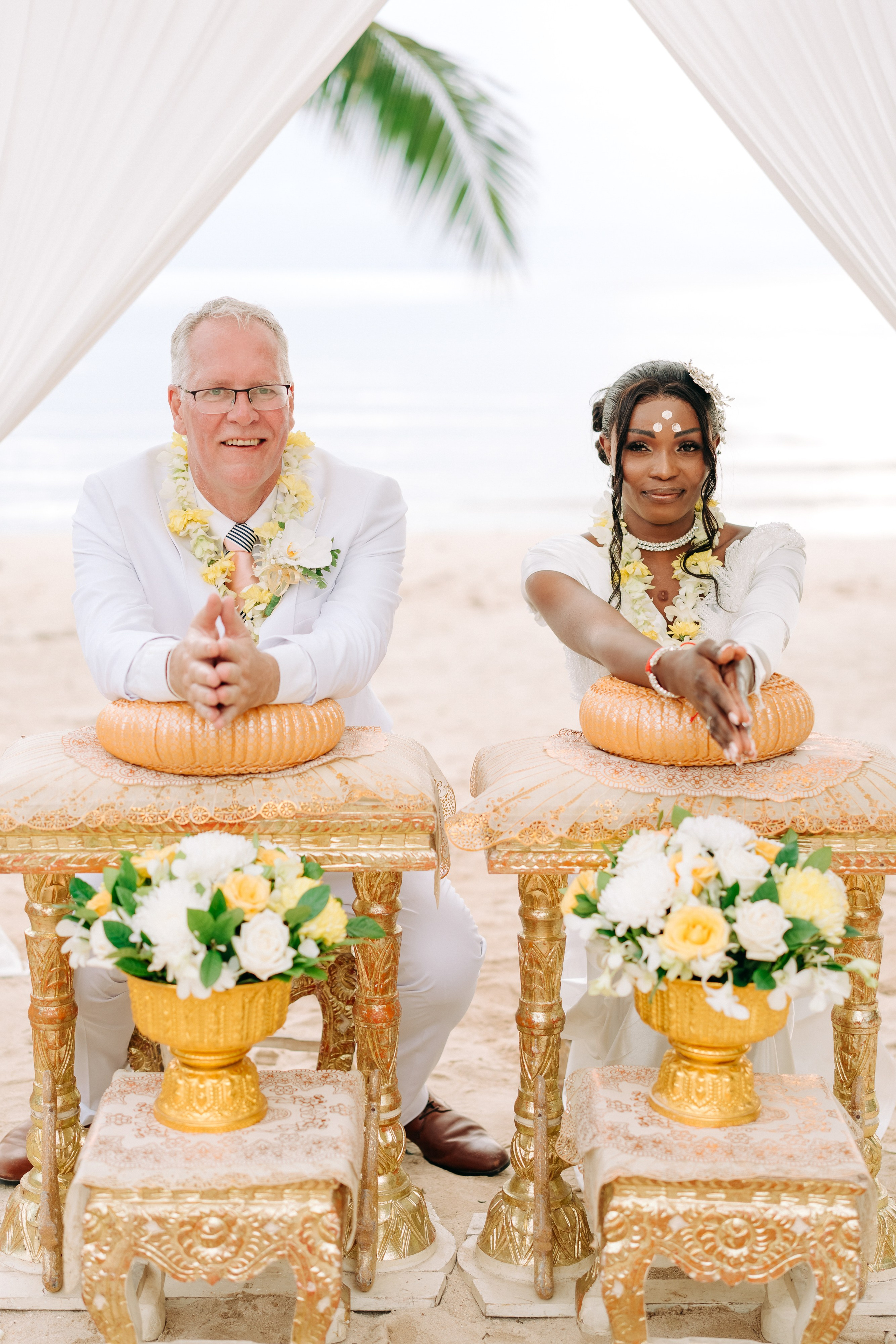 Bride and groom participating in a sacred Buddhist blessing ceremony by the sea in Koh Samui, Thailand.