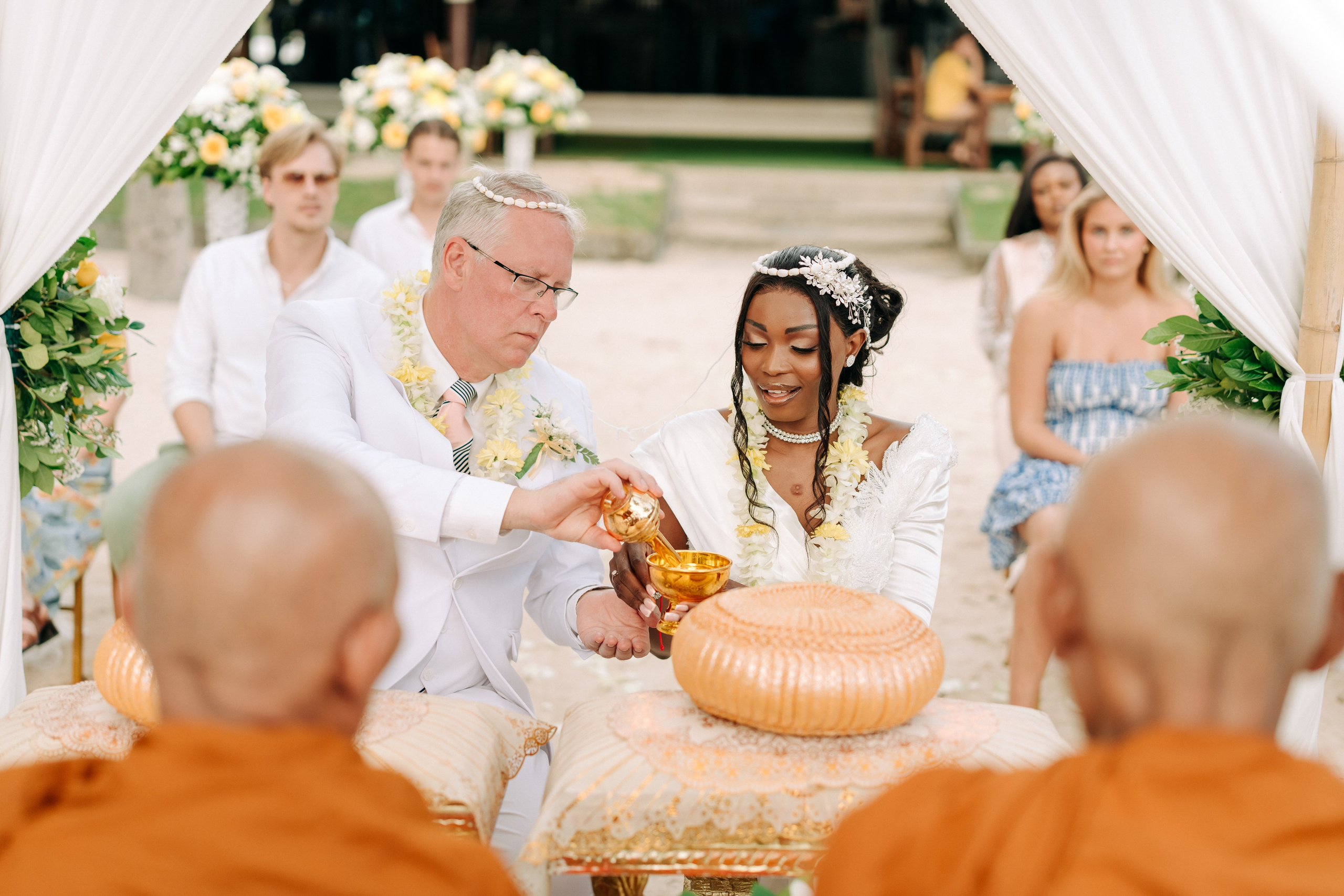 Bride and groom participating in a sacred Buddhist blessing ceremony by the sea in Koh Samui, Thailand.