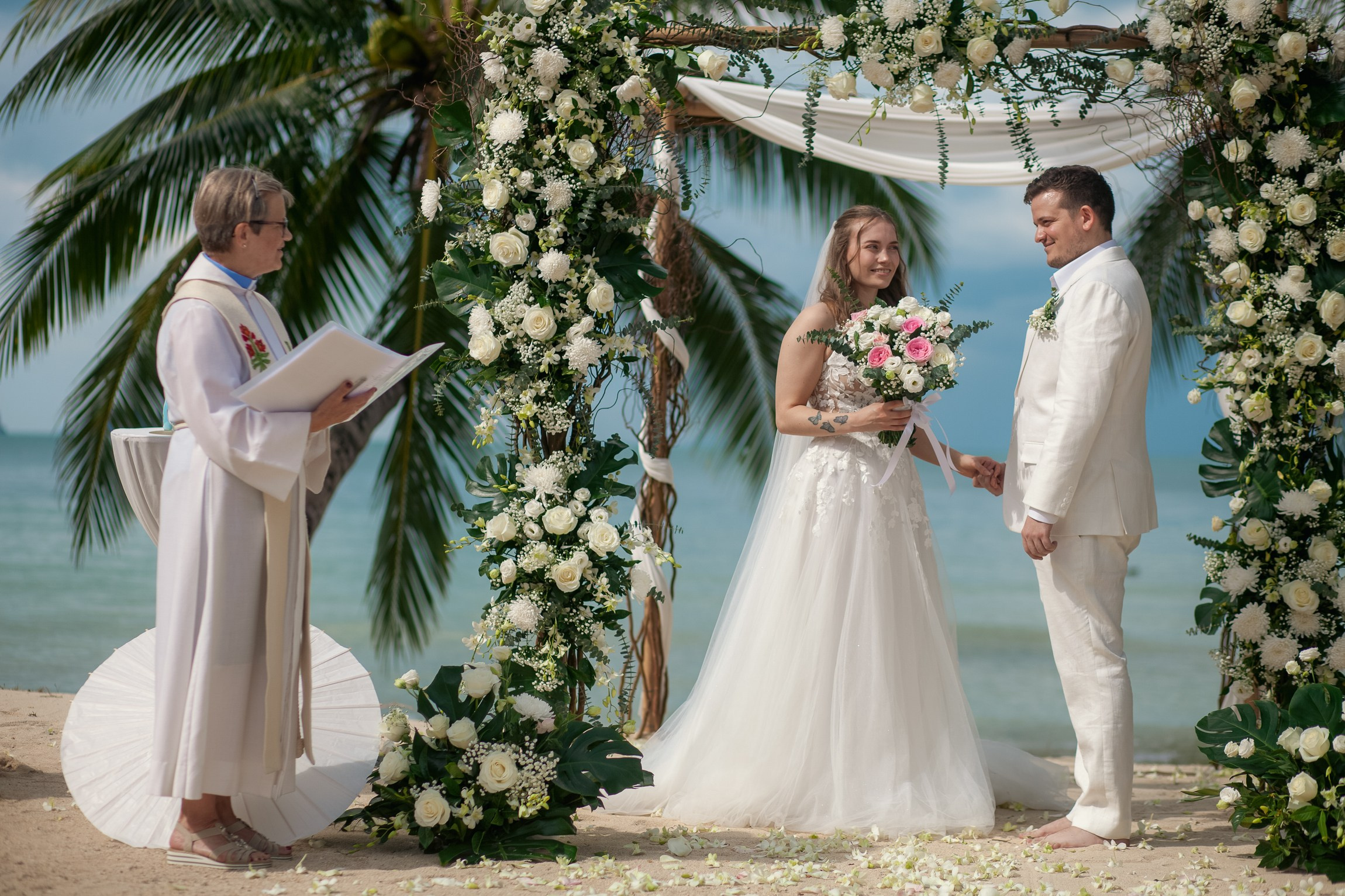 Bride and groom celebrating a beach wedding with their children in Koh Samui, Thailand, surrounded by tropical scenery and ocean views