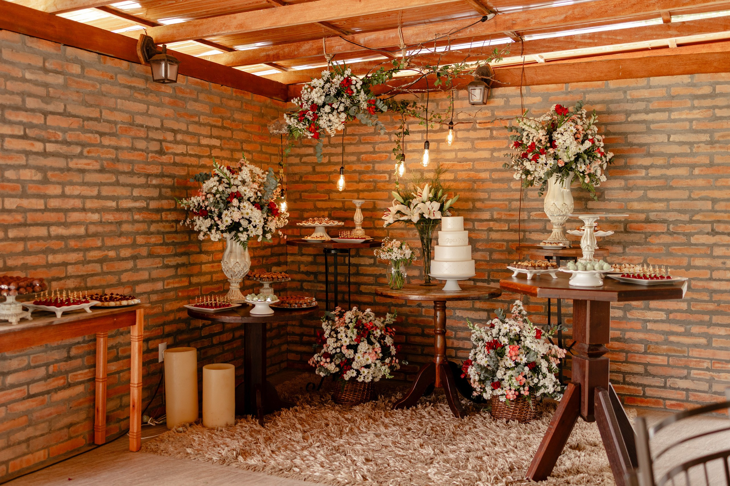 Fotógrafo de casamento em Santa Catarina; mesa de doces decorada com bolo branco e arranjos florais em recepção ao ar livre.