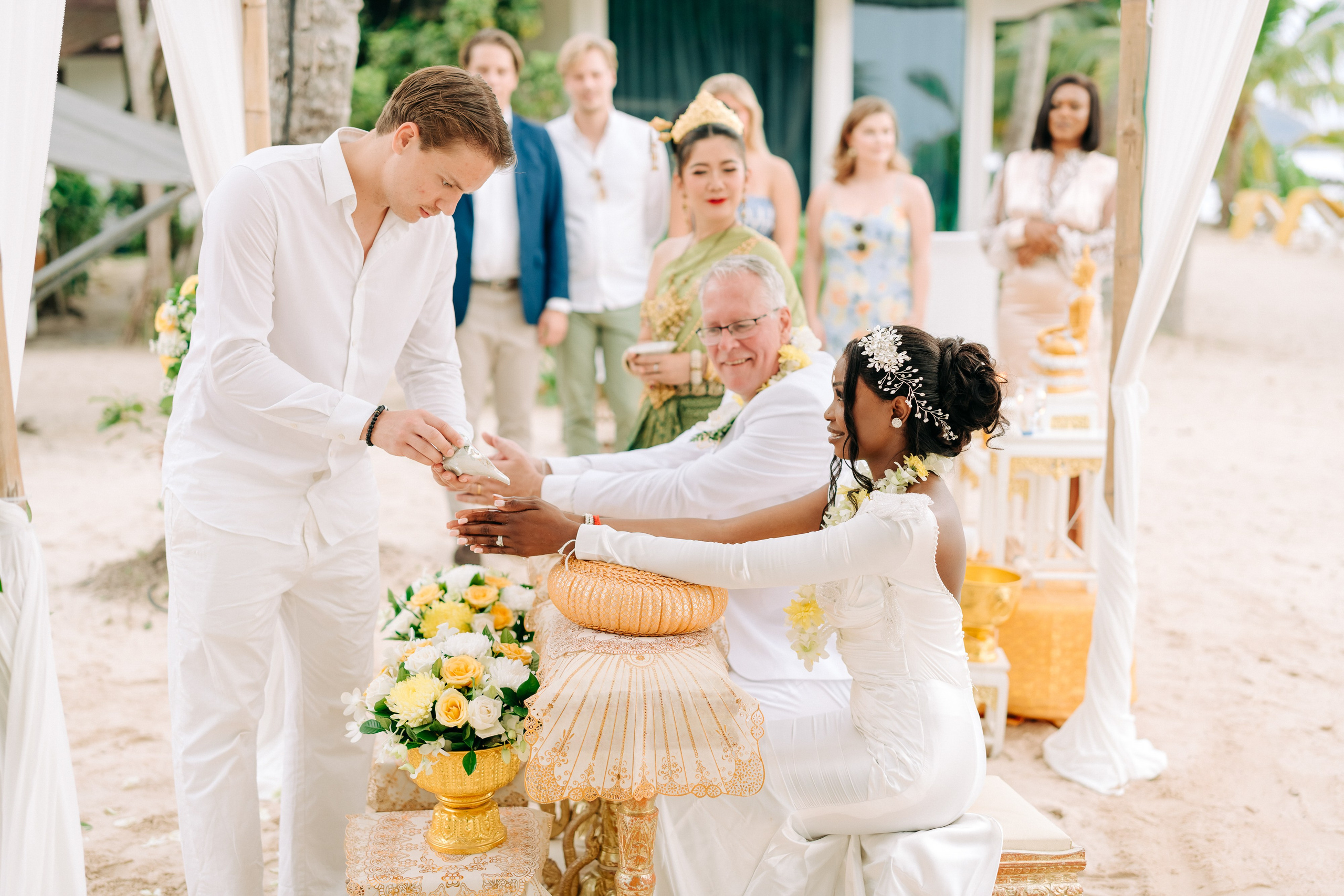Newlywed couple celebrating a Buddhist wedding ceremony on a beautiful beach in Koh Samui, Thailand.