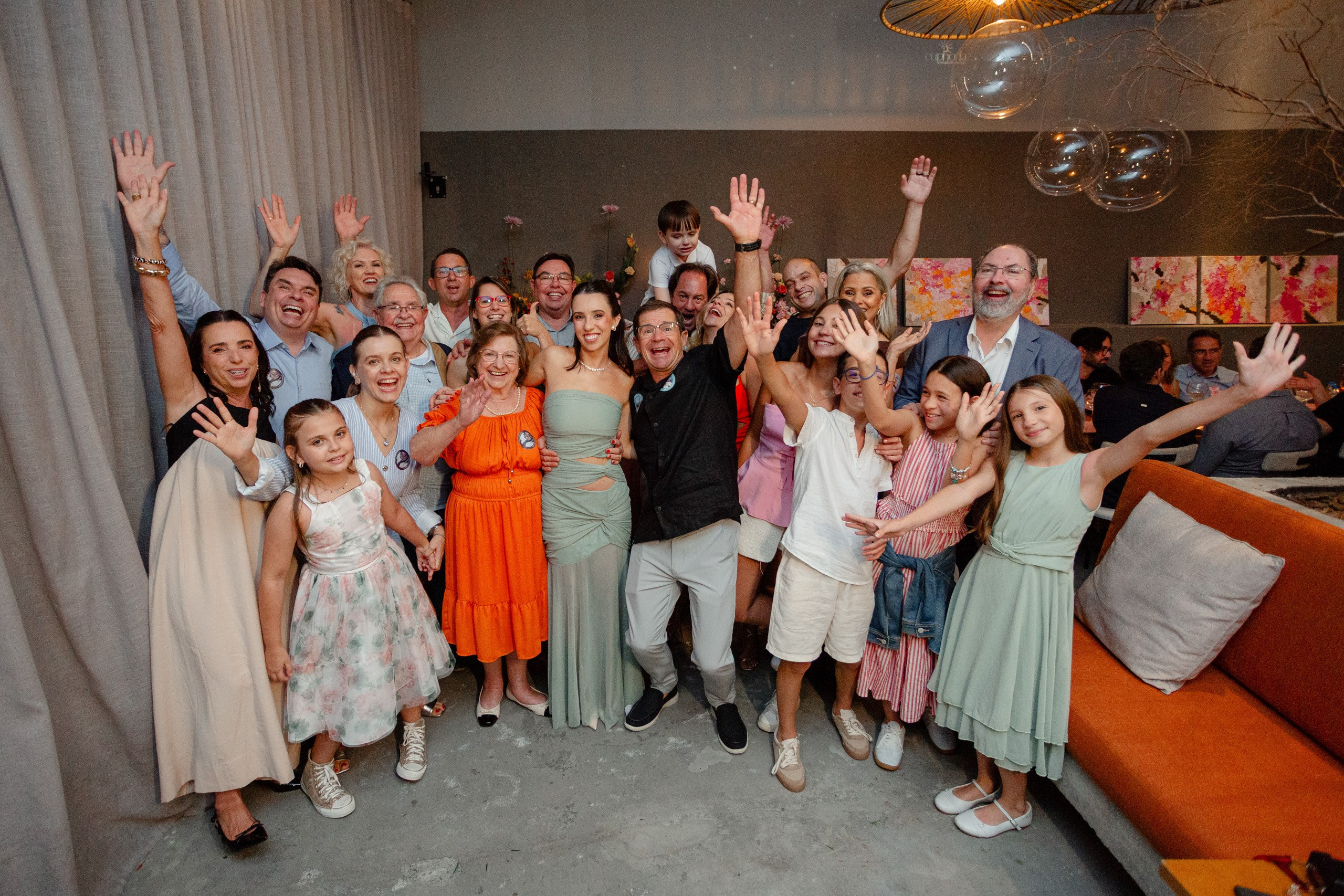 Fotógrafo de festa de formatura em Balneário Camboriú; grupo grande de convidados e formanda sorrindo para a câmera durante a recepção festiva.