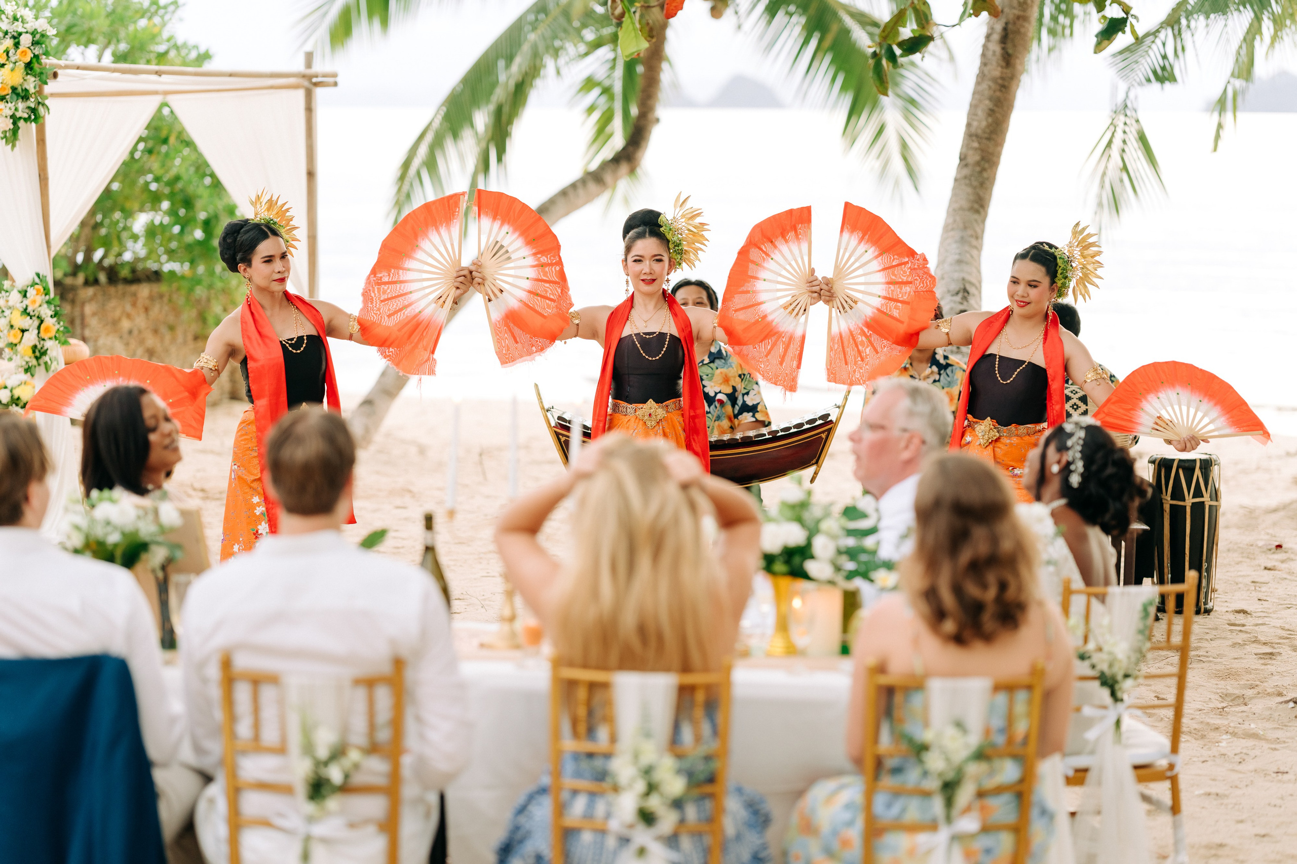 Couple taking part in a traditional Buddhist wedding ceremony on a tropical beach in Koh Samui, Thailand, with monks, flowers, and ocean views.