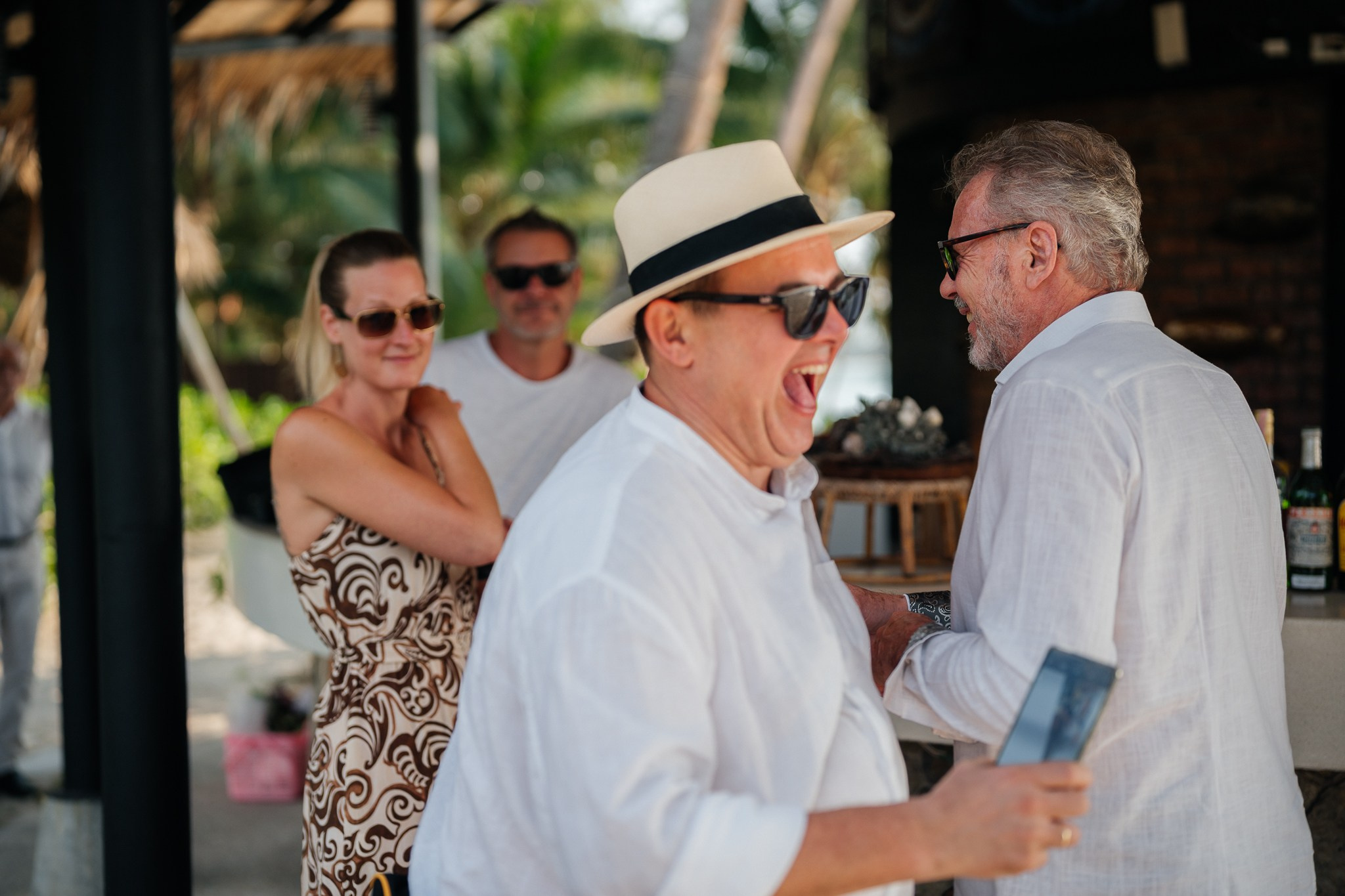 Bride and groom celebrating a beautiful beach wedding in Koh Samui, Thailand, surrounded by friends and family with tropical ocean views