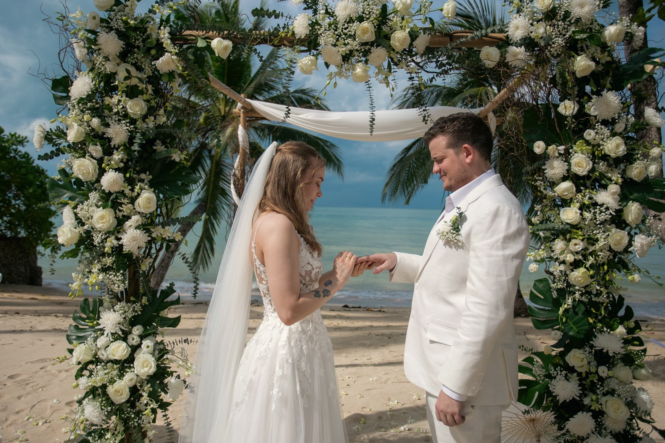 Romantic destination wedding on Koh Samui beach with tropical flowers, ocean views and happy newlyweds