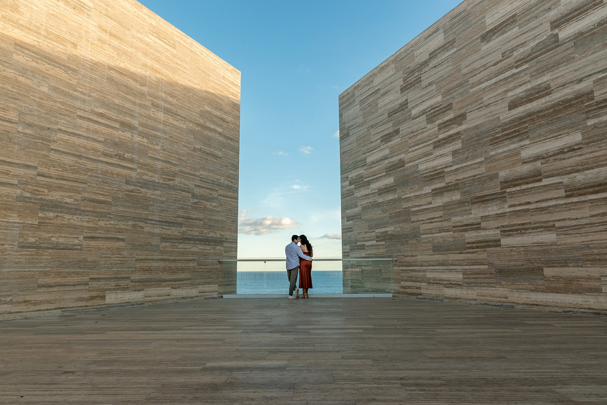 Romantic couple session in Los Cabos – intimate embrace between stone walls with ocean view at sunset