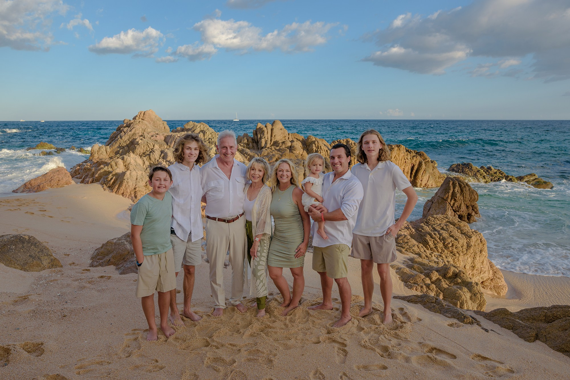 Multi generation family portrait in San Jose del Cabo – grandparents with family by the ocean and rock formations at Fiesta Americana