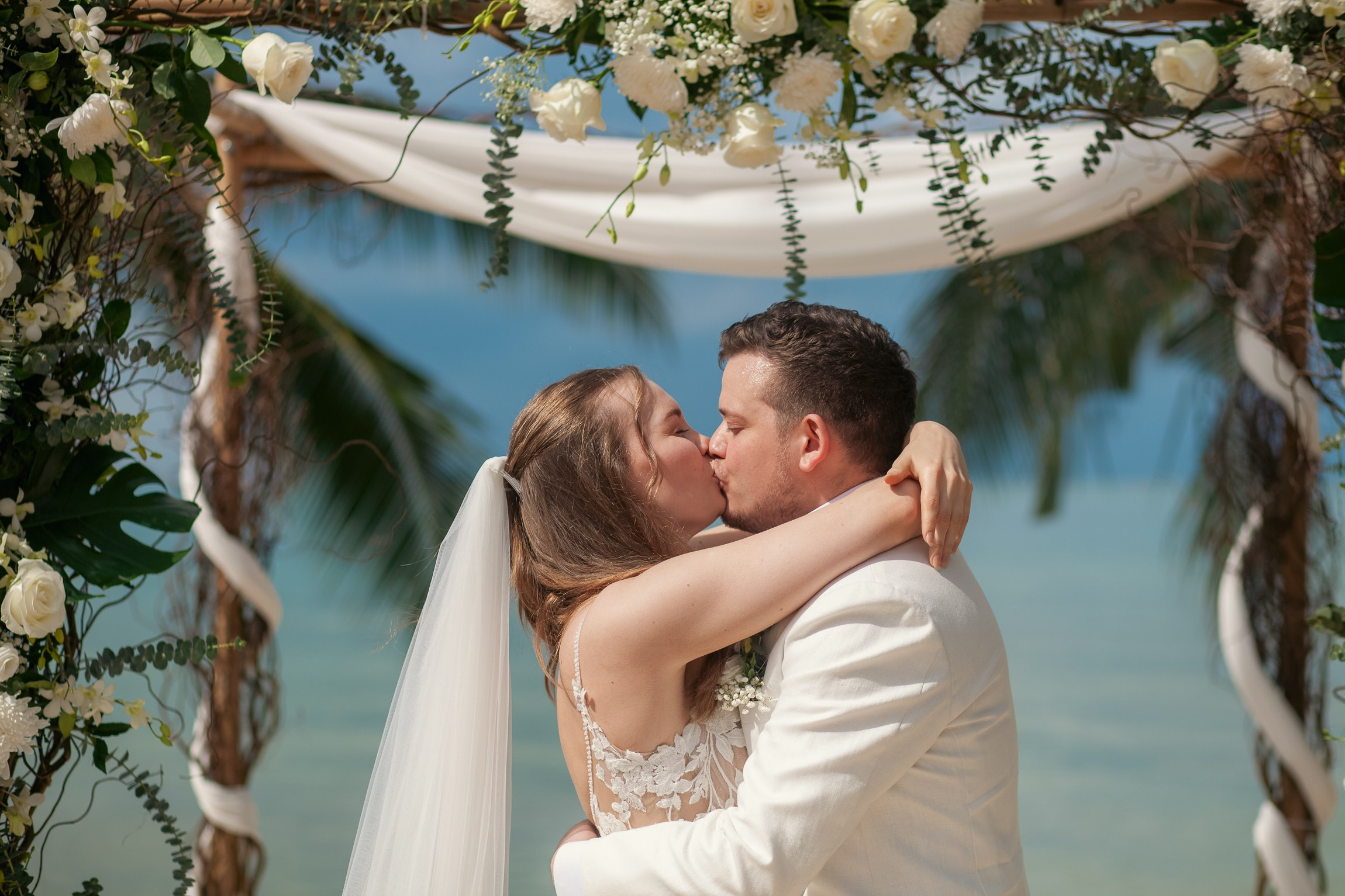 Bride and groom celebrating a beach wedding with their children in Koh Samui, Thailand, surrounded by tropical scenery and ocean views