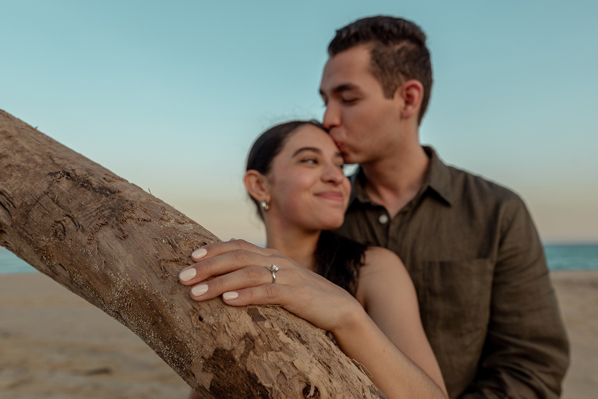 Engagement photoshoot in Los Cabos – close up of engagement ring as groom embraces bride to be at sunset by the sea, romantic proposal photographer Cabo San Lucas