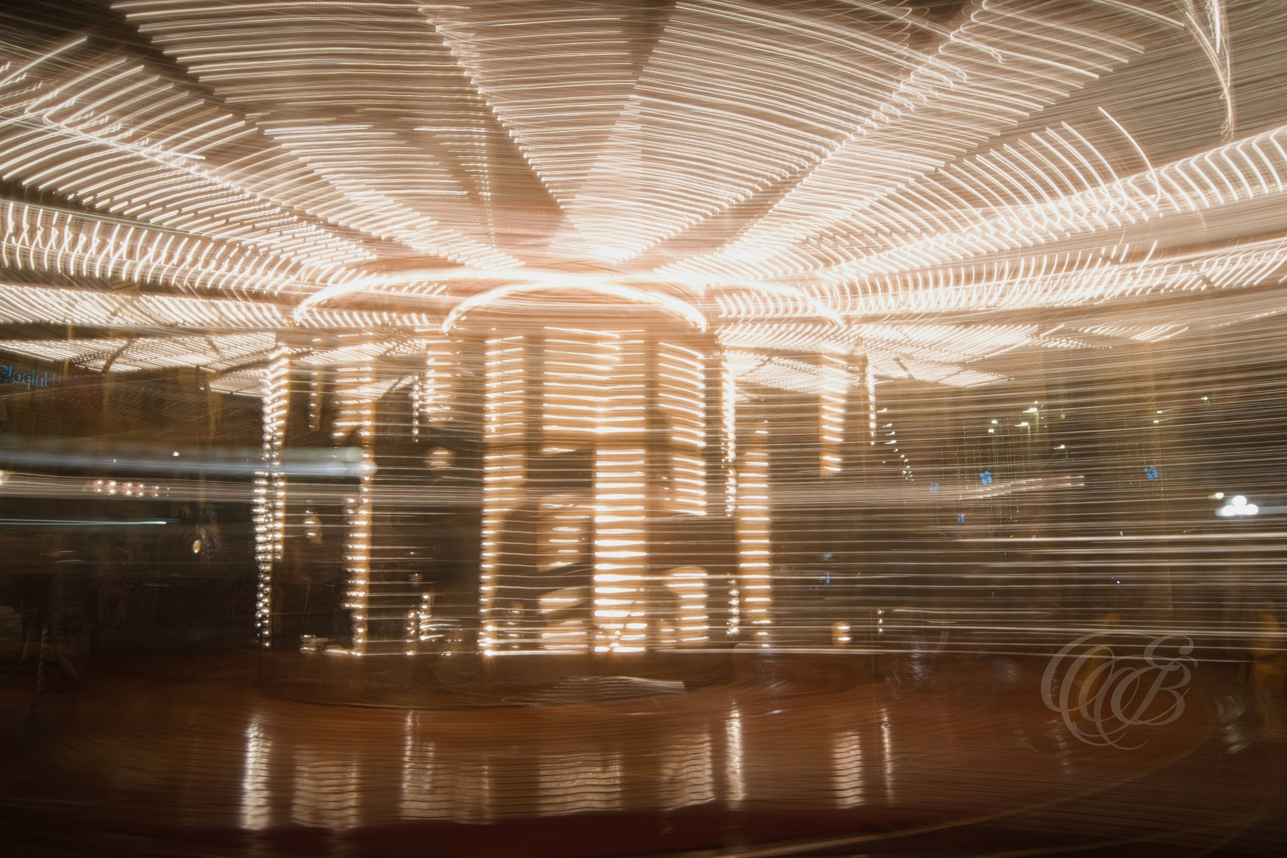Florence, Italy – Long exposure of a moving carousel with light trails, capturing motion blur and illuminated ride at night in an urban setting – Eduardo Bartoli Photography.