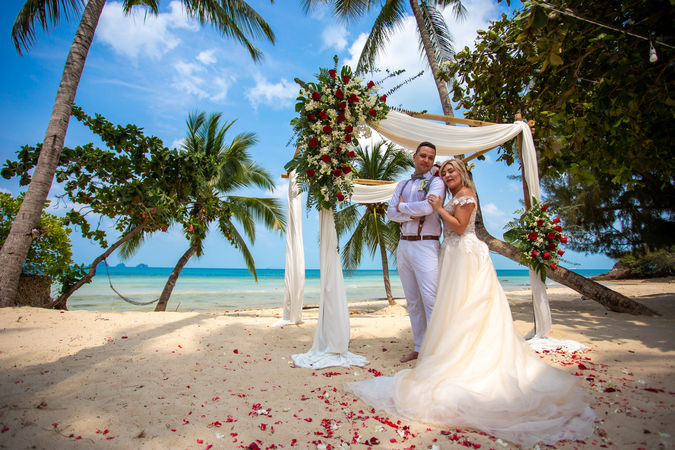 Elegant beach wedding setup on Koh Samui, Thailand with bride, groom, flowers and stunning sea backdrop