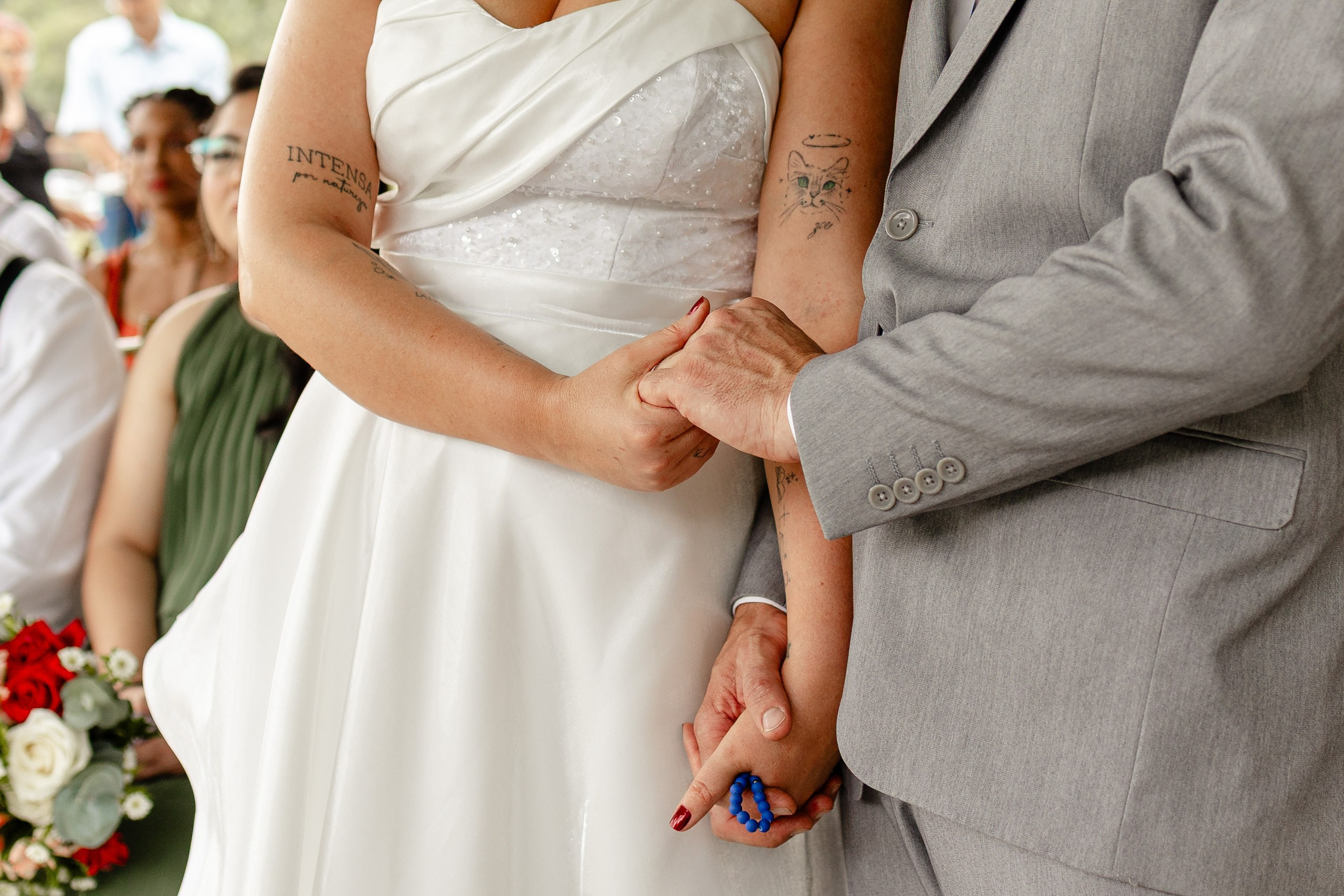 Fotógrafo de casamento em Santa Catarina; close detalhe das mãos dos noivos entrelaçadas durante a cerimônia no campo.