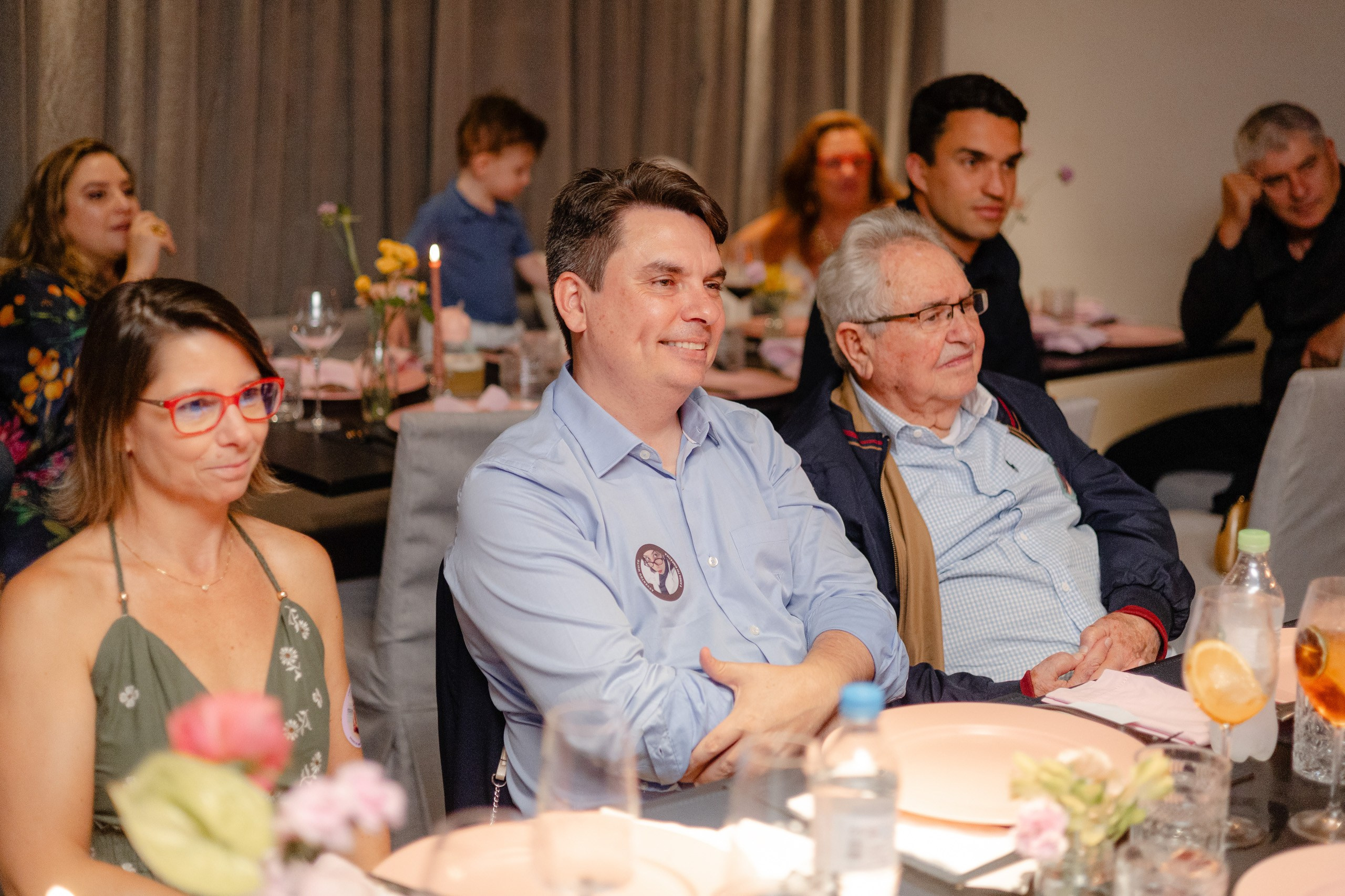 Fotógrafo de festa de formatura em Balneário Camboriú; convidados sorridentes sentados à mesa durante o jantar da recepção.