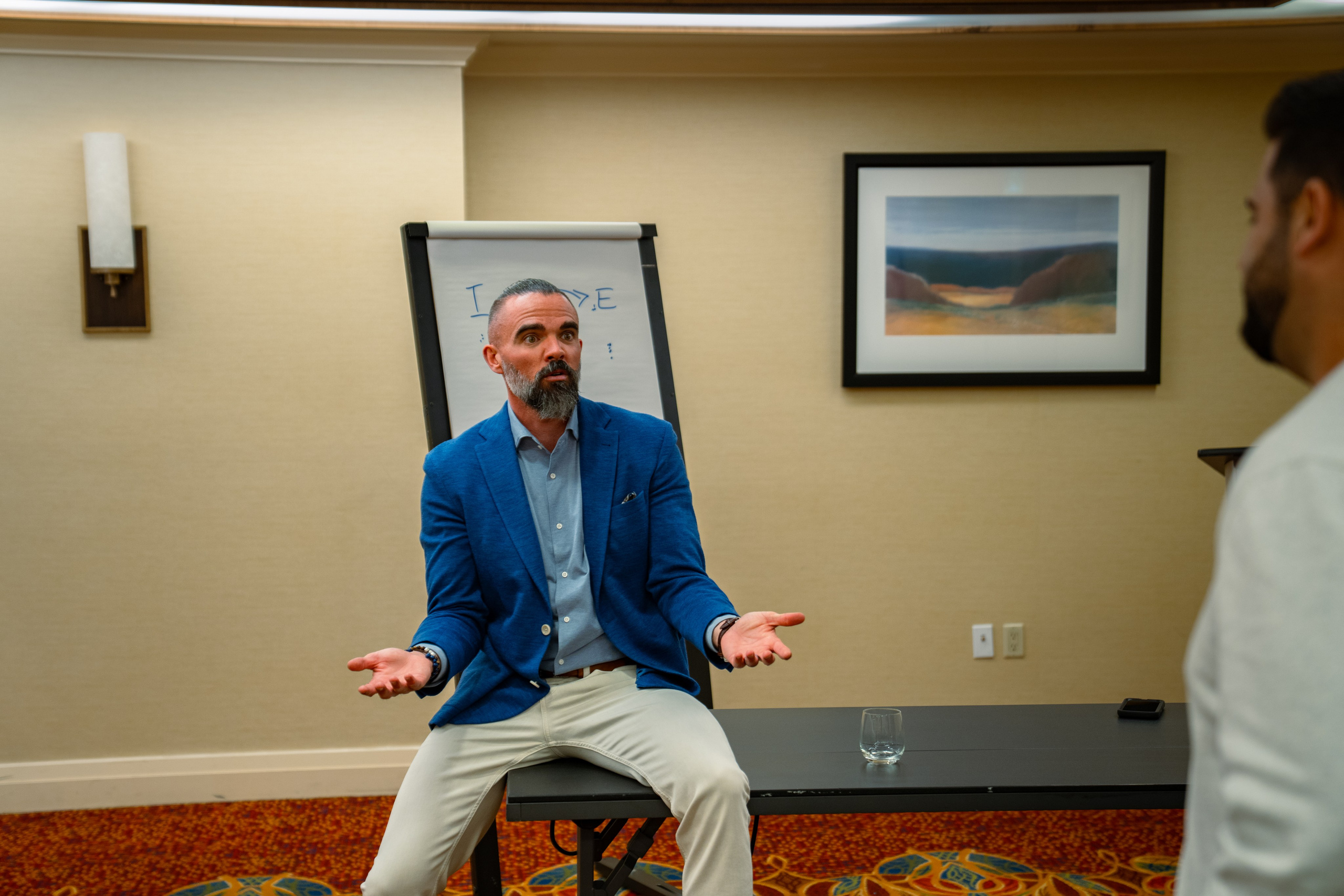 Matt Poechman seated speaking with attendee at event