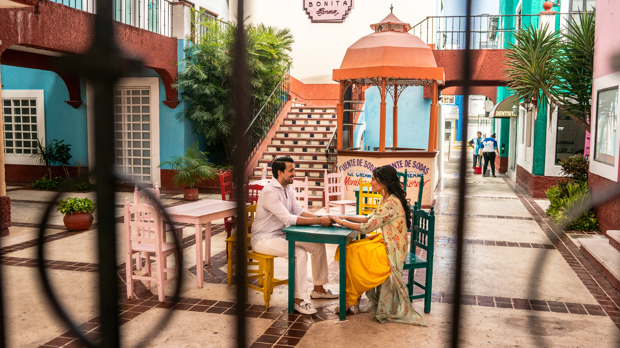 Travel couple enjoying a casual photoshoot in Cancún with vibrant architecture and tropical ambiance.