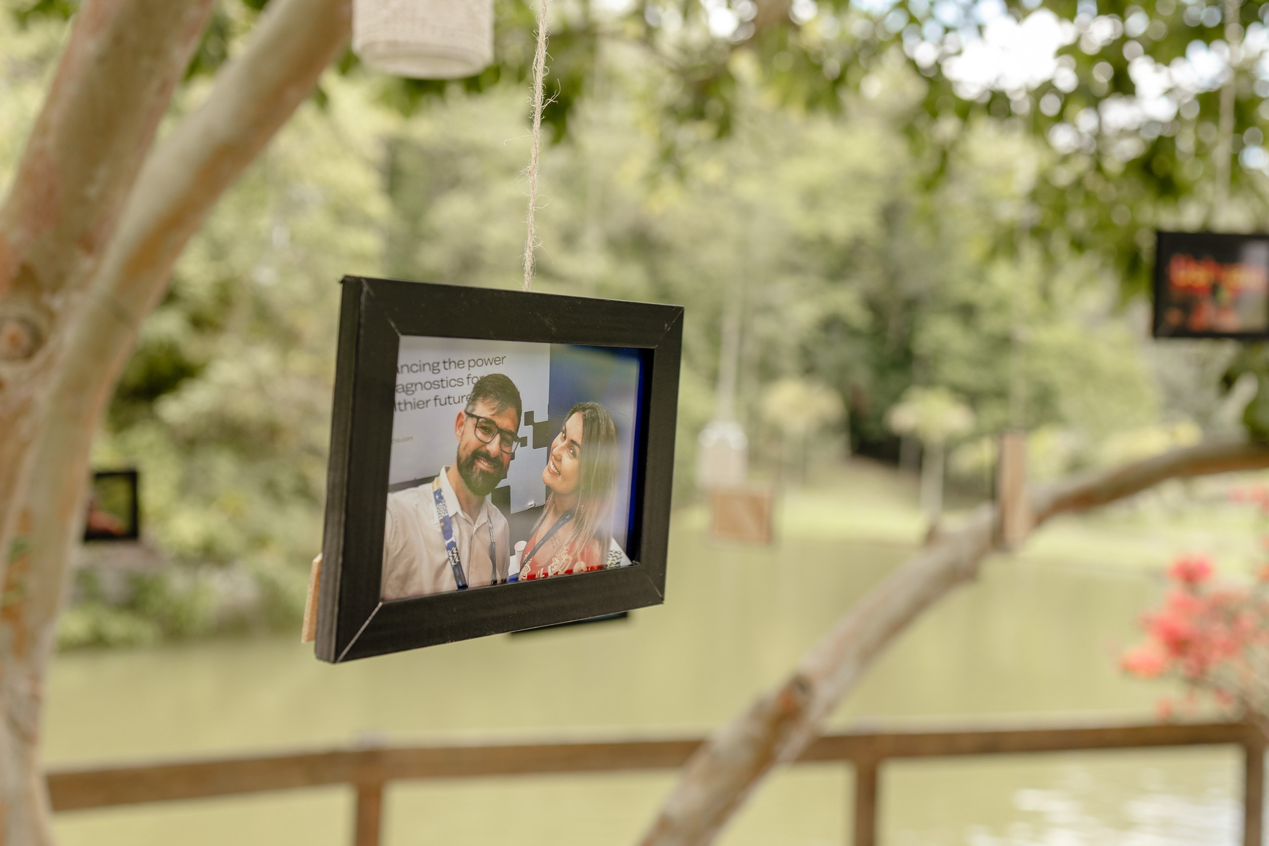 Fotógrafo de casamento em Santa Catarina; retrato de casal em porta-retrato pendurado na árvore durante decoração de cerimônia ao ar livre.