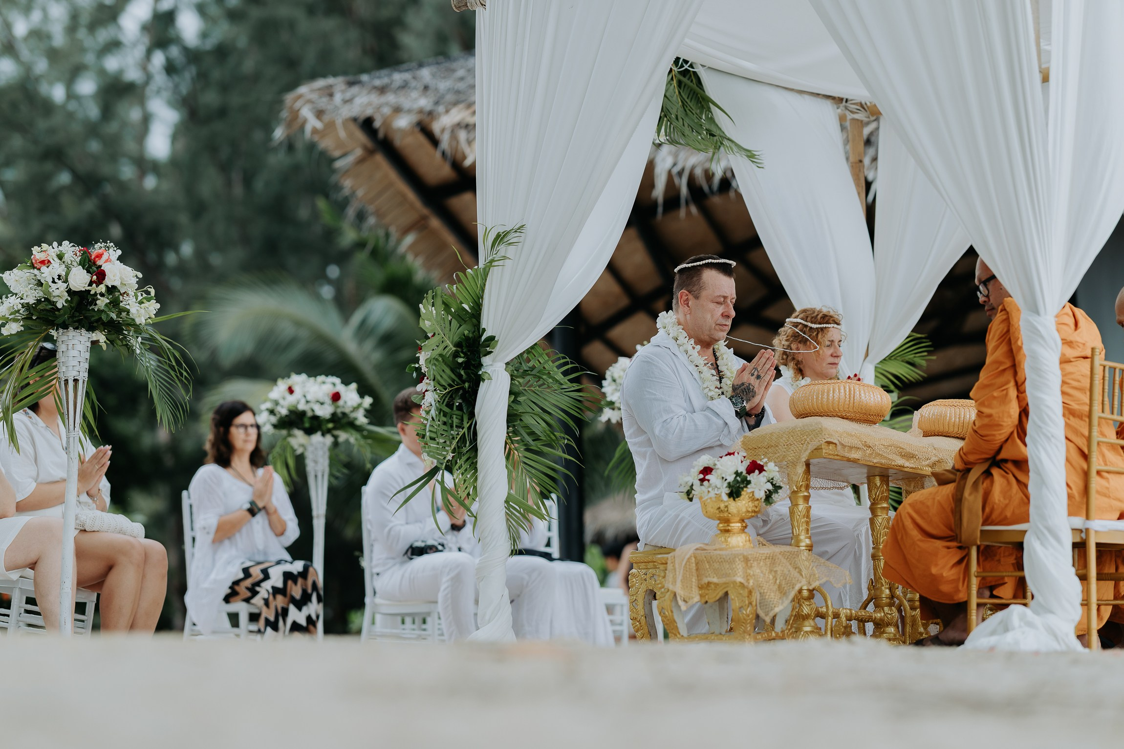 Bride and groom participating in a sacred Buddhist wedding blessing in Thailand