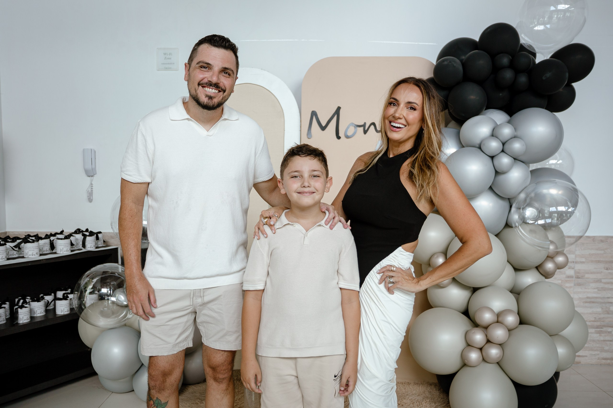 Fotografia de cobertura de festa de aniversário em Itajaí retratando a família posando unida e sorridente em frente a um painel decorado com balões.