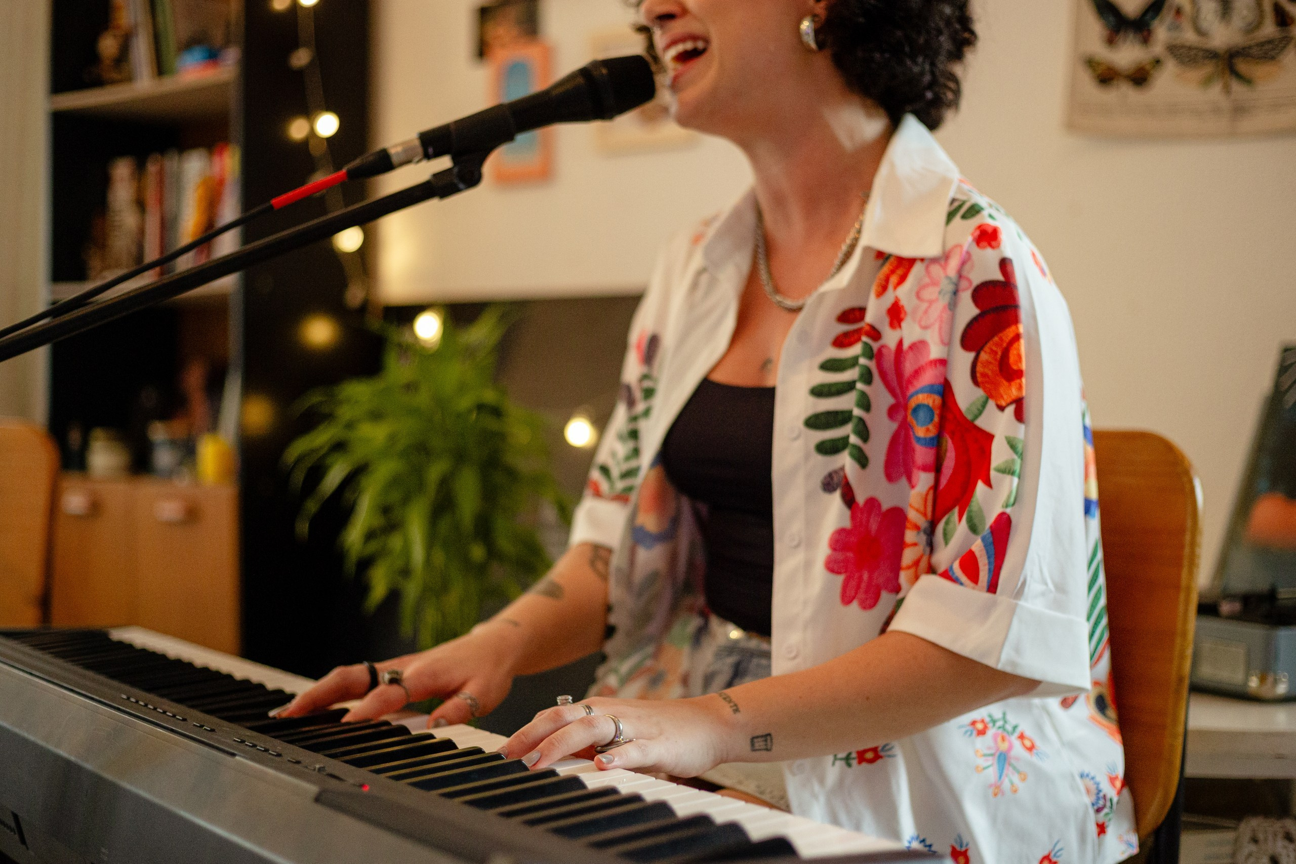 Cantora tocando teclado e cantando ao microfone durante cobertura fotográfica de show em Itajaí.
