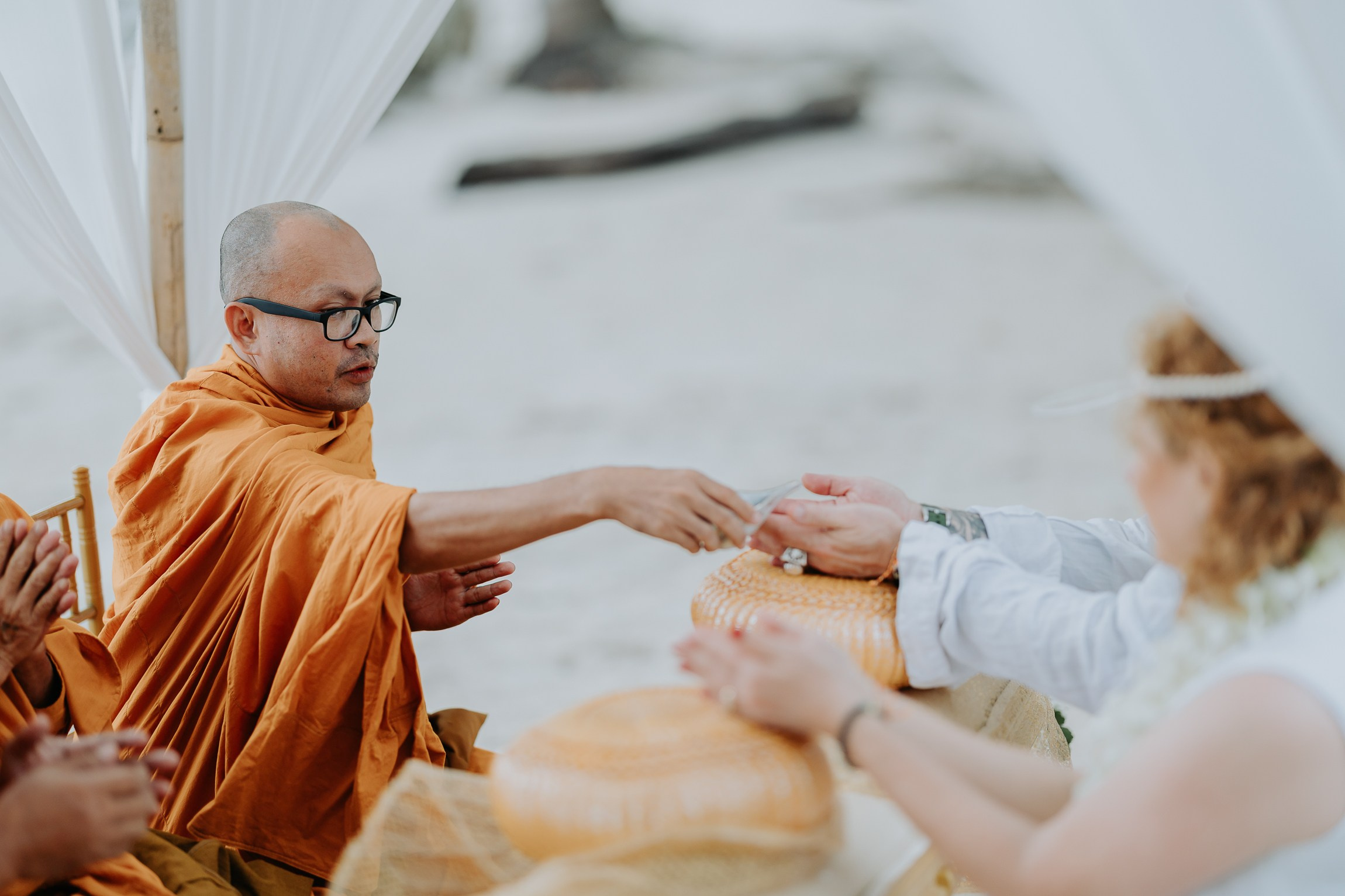 Bride and groom participating in a sacred Buddhist wedding blessing in Thailand