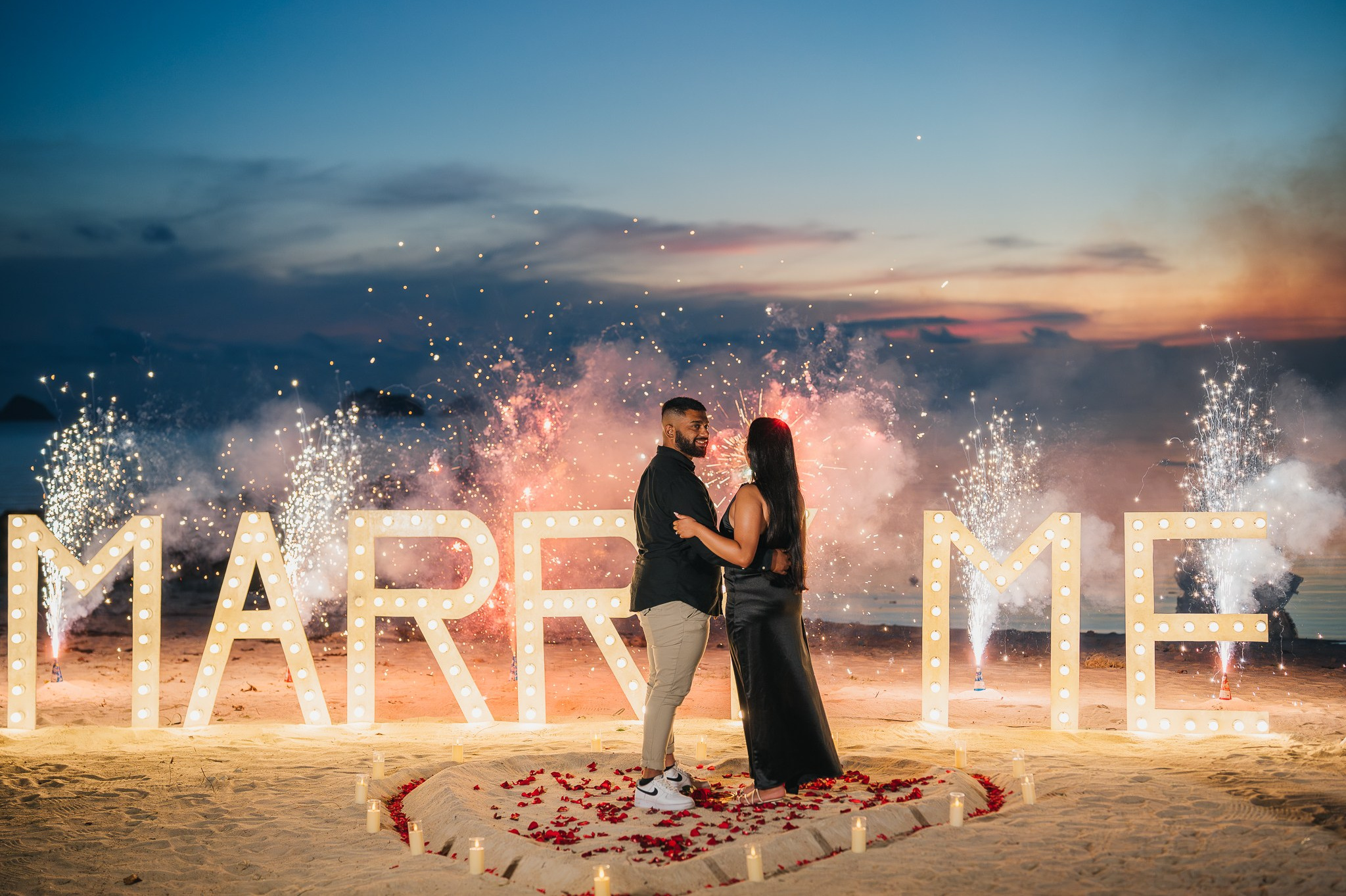 Elegant “Marry Me” beach proposal setup in Koh Samui with rose petals and tropical decor.
