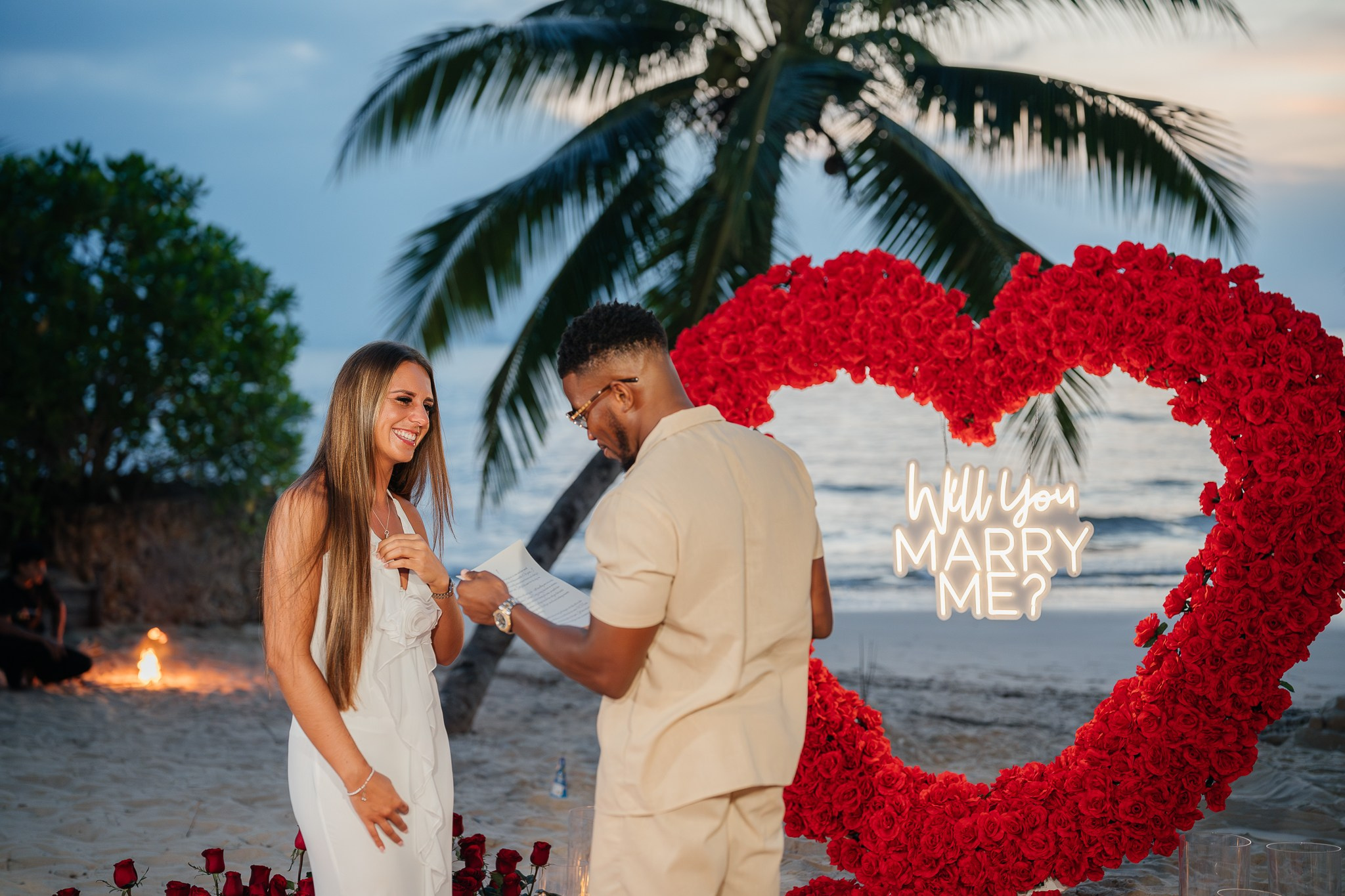 Romantic beach proposal setup in Koh Samui, Thailand with candles, flowers and ocean sunset view.
