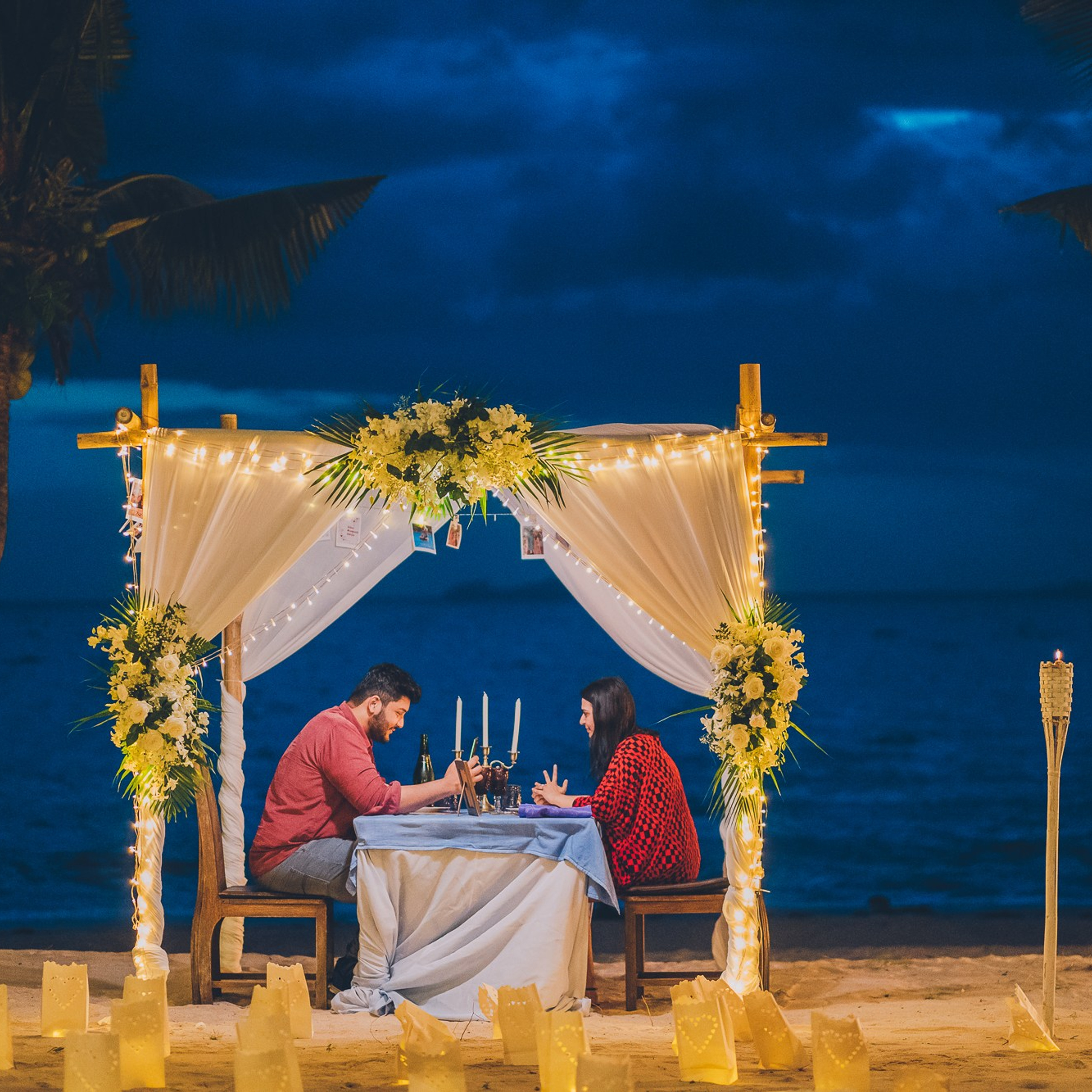 Romantic beach proposal setup in Koh Samui with candles and flower arch.
