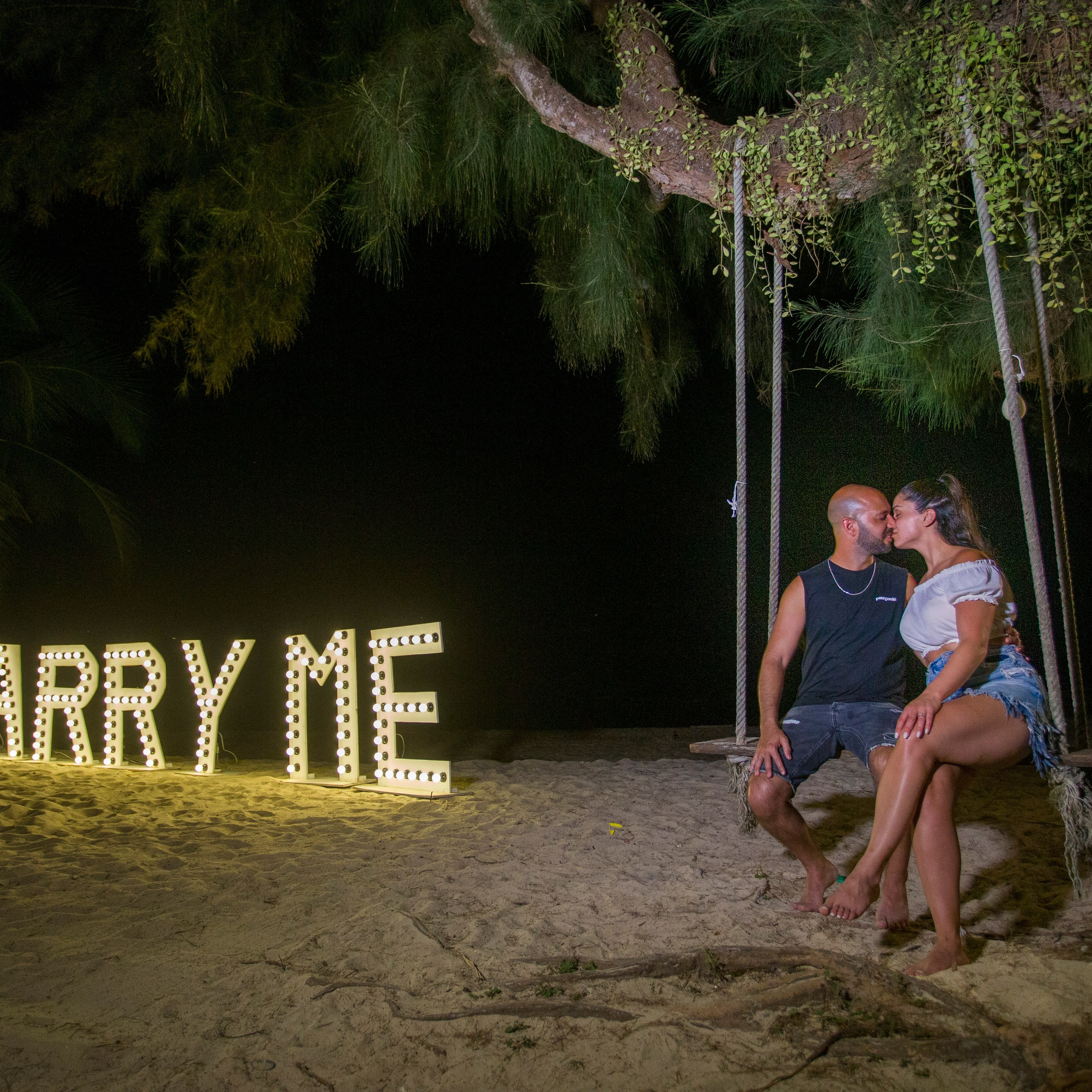 Romantic beach proposal setup in Koh Samui with candles and flower arch.