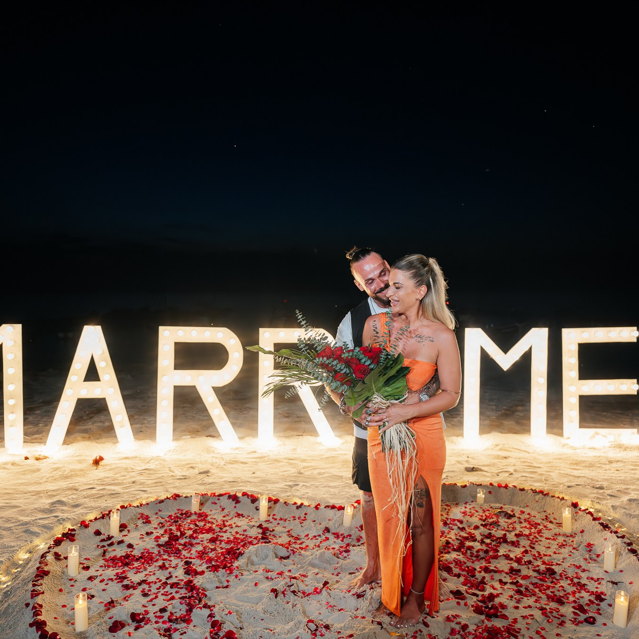 Romantic beach proposal setup in Koh Samui with candles and flower arch.