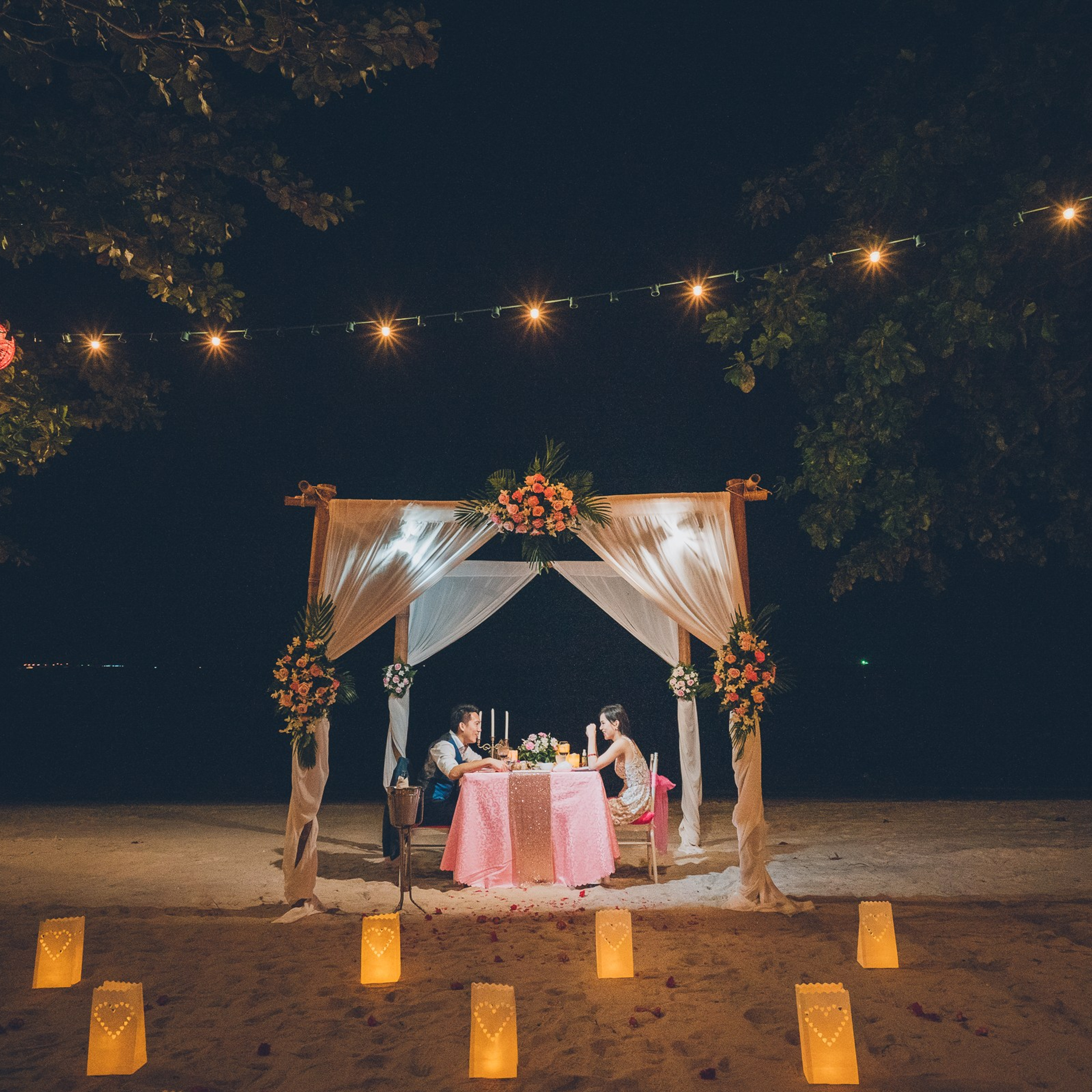 Romantic beach proposal setup in Koh Samui with candles and flower arch.