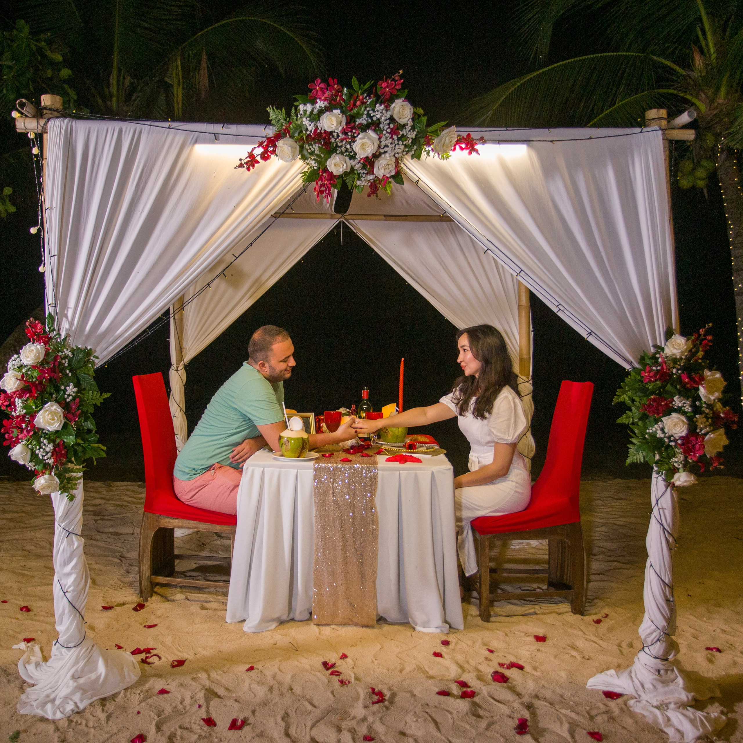 Romantic beach proposal setup in Koh Samui with candles and flower arch.