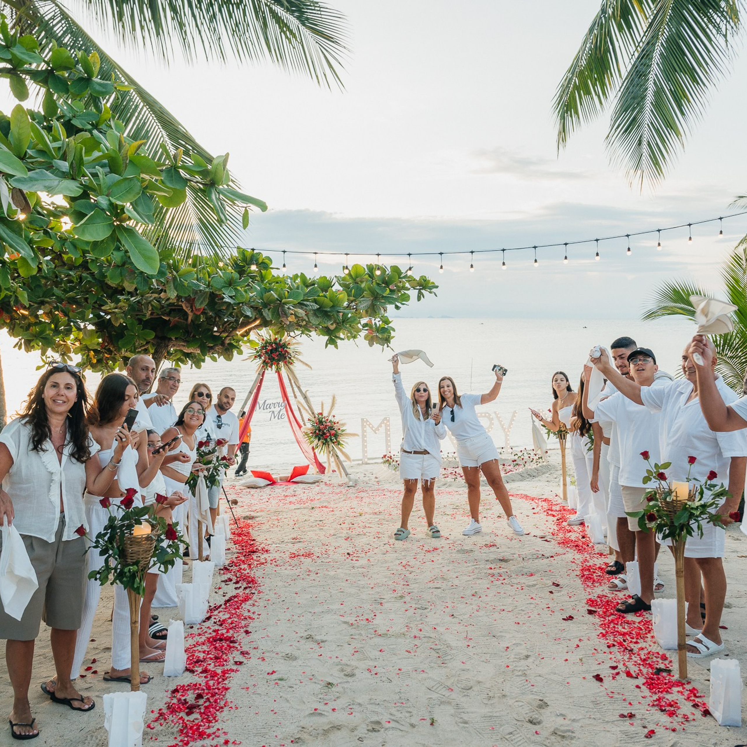 Romantic beach proposal setup in Koh Samui with candles and flower arch.