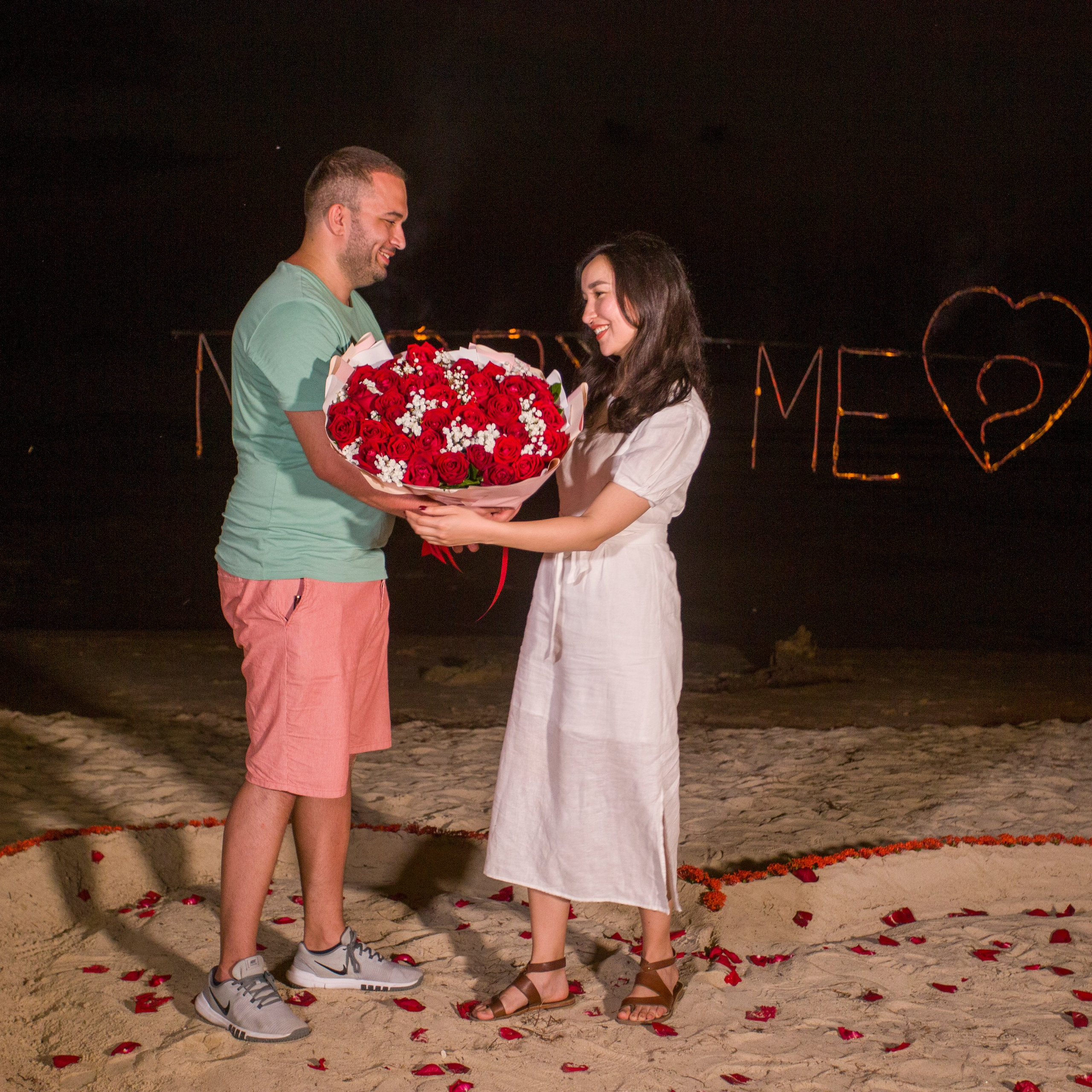 Romantic beach proposal setup in Koh Samui with candles and flower arch.