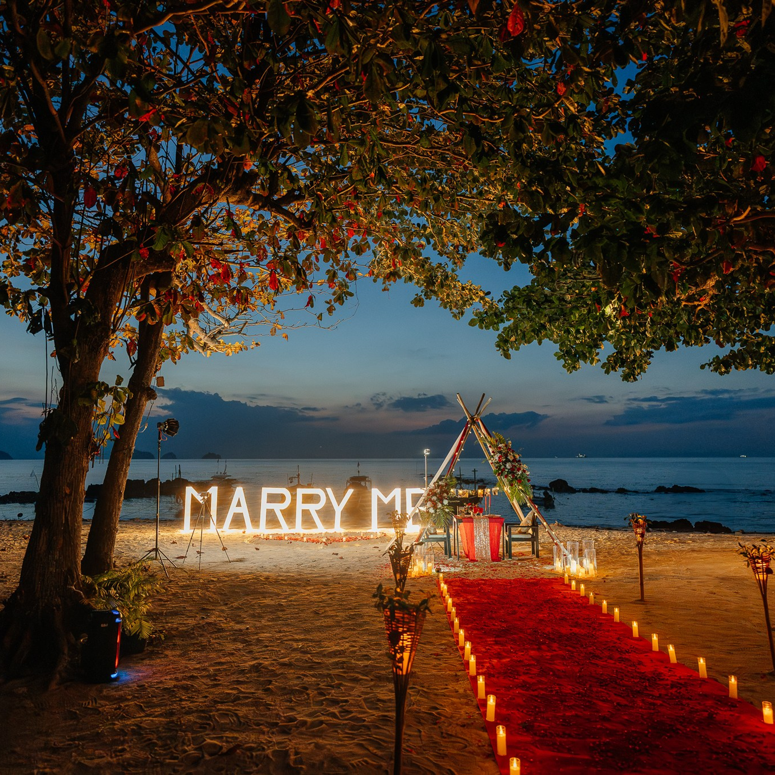 Romantic beach proposal setup in Koh Samui with candles and flower arch.