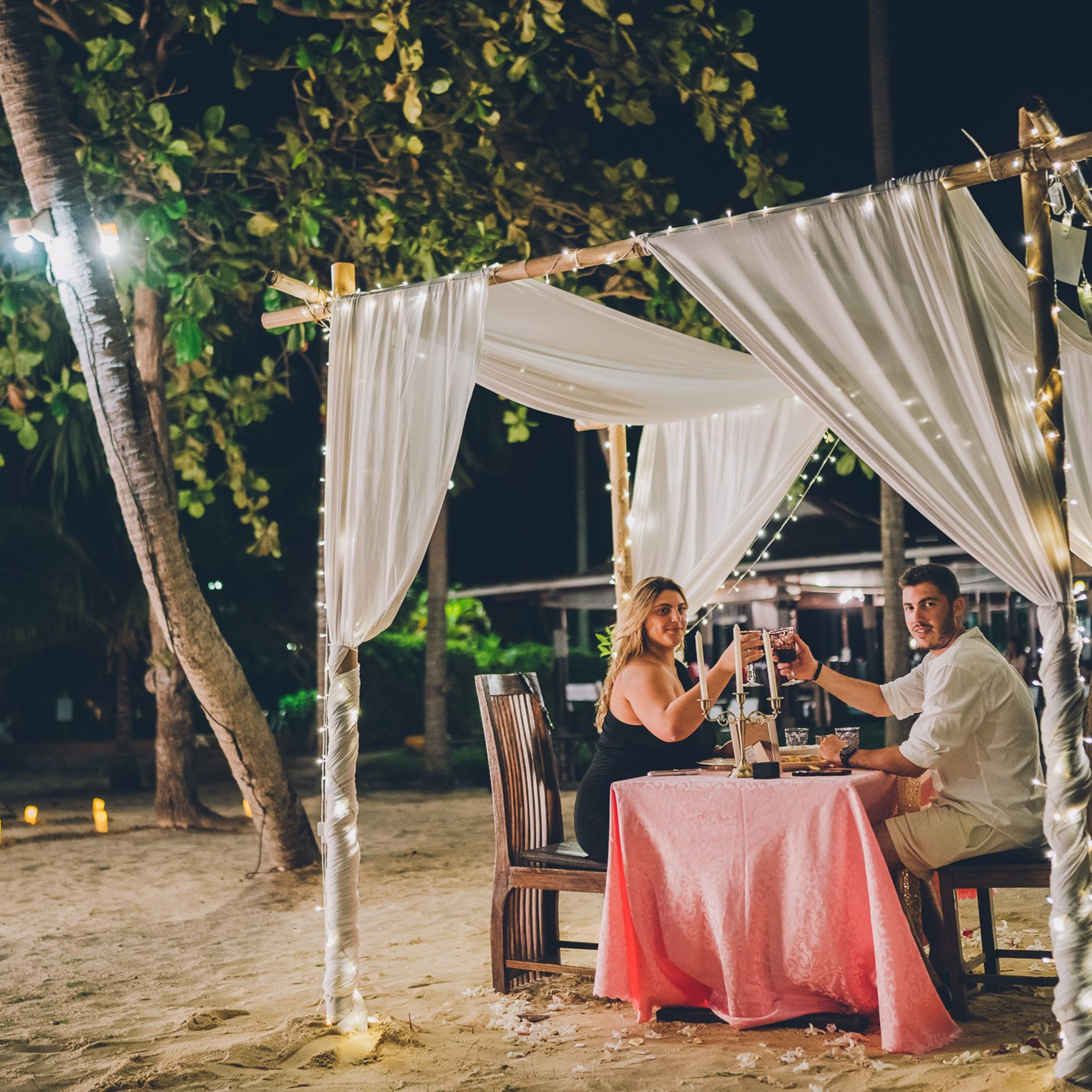 Romantic beach proposal setup in Koh Samui with candles and flower arch.