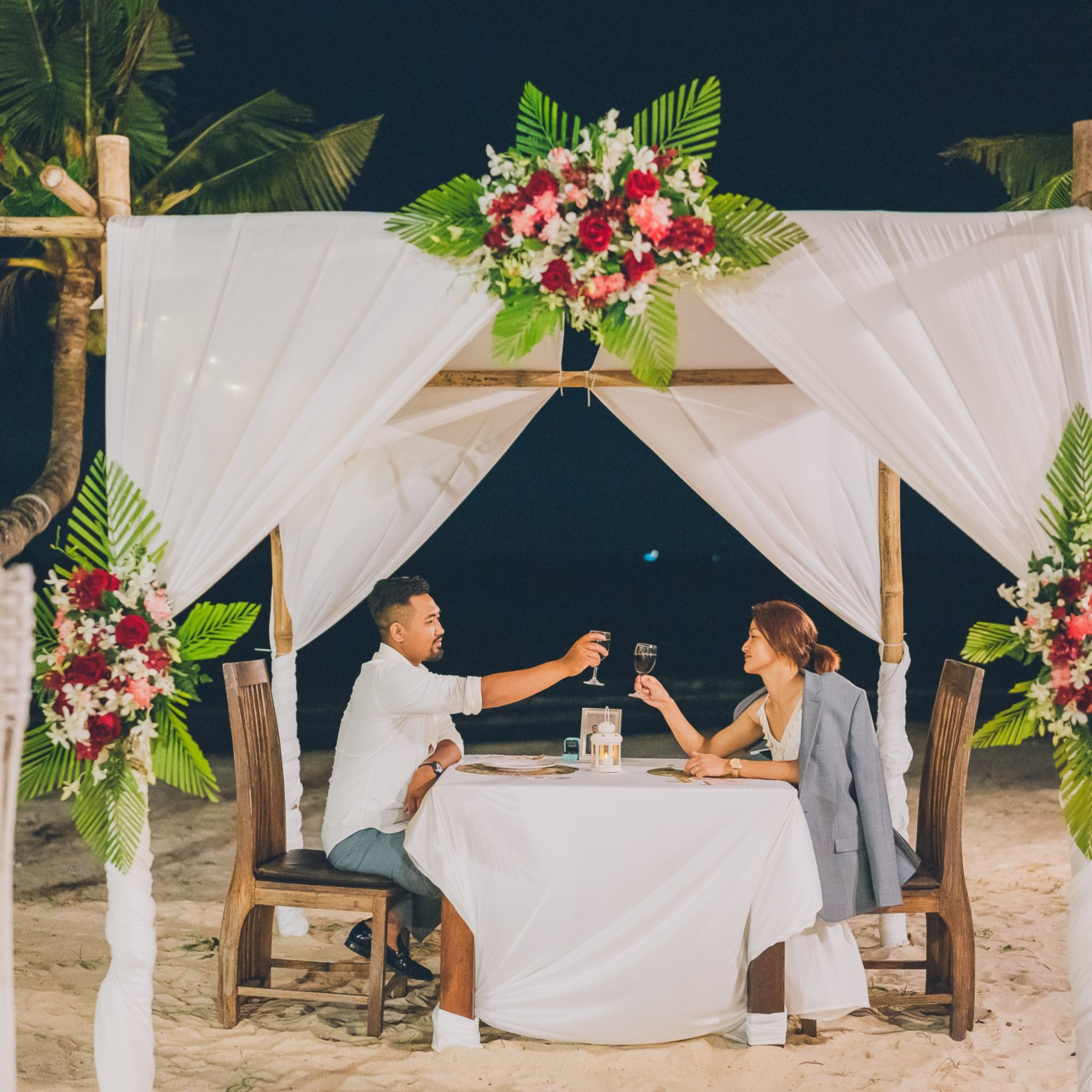 Romantic beach proposal setup in Koh Samui with candles and flower arch.