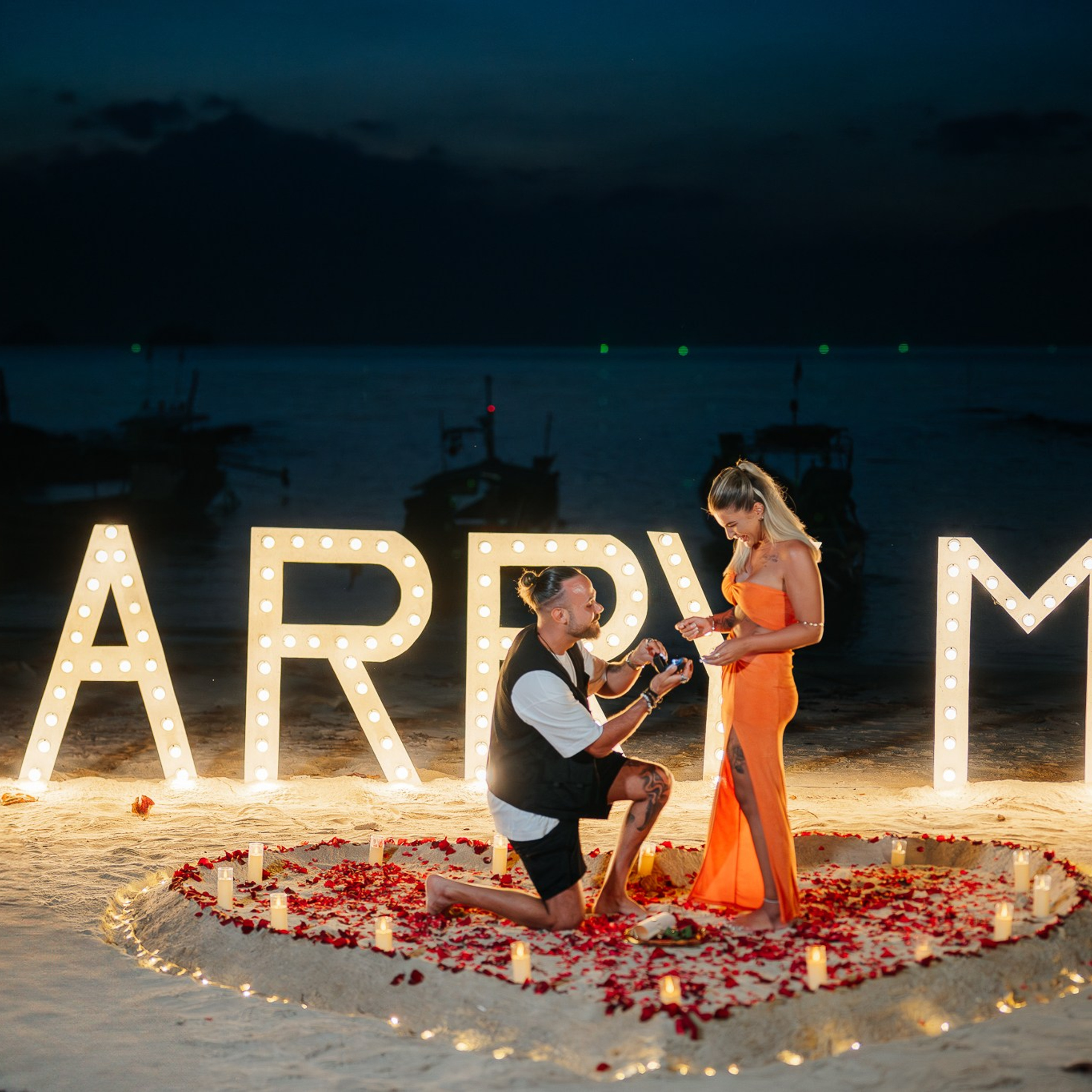 Romantic beach proposal setup in Koh Samui with candles and flower arch.