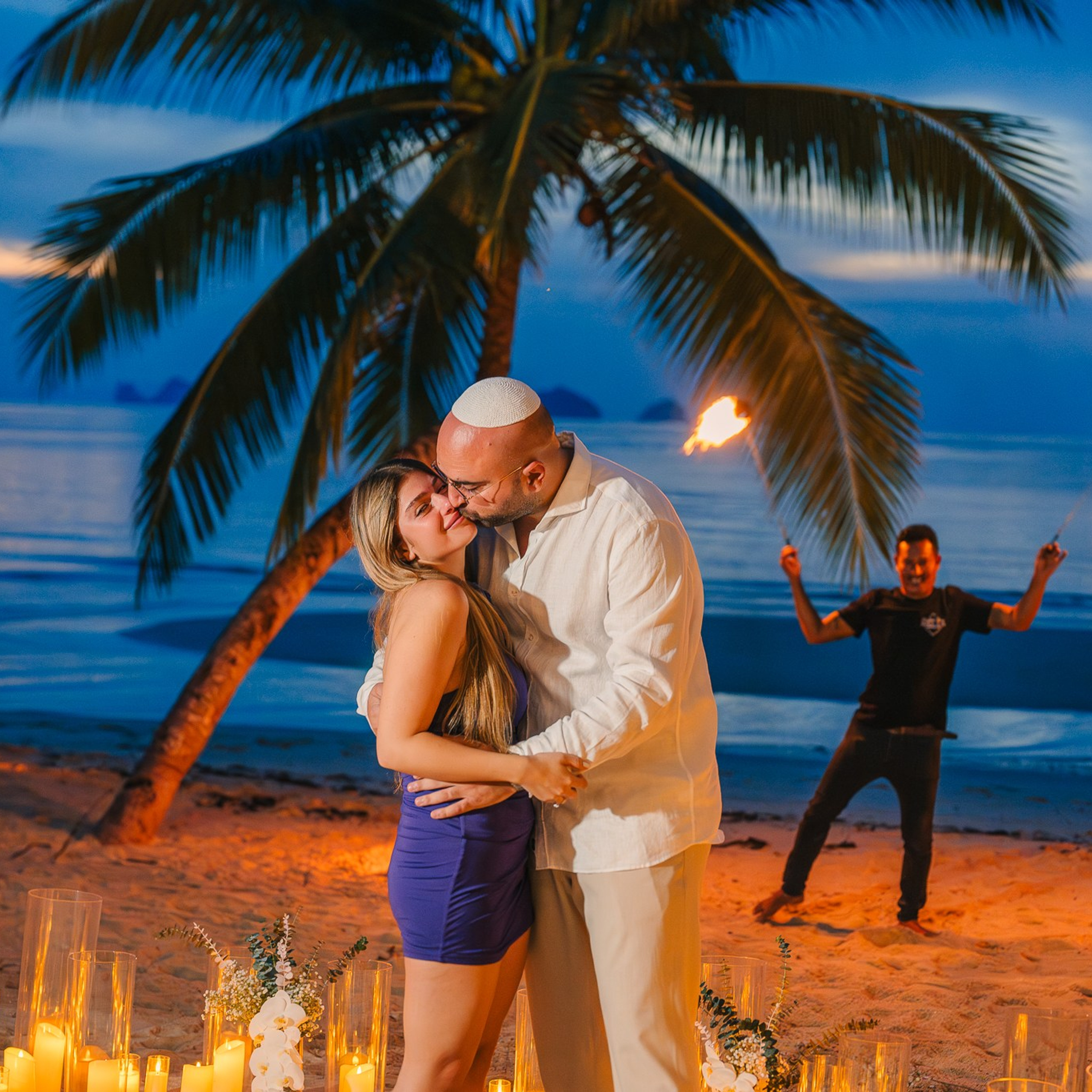 Romantic beach proposal setup in Koh Samui with candles and flower arch.