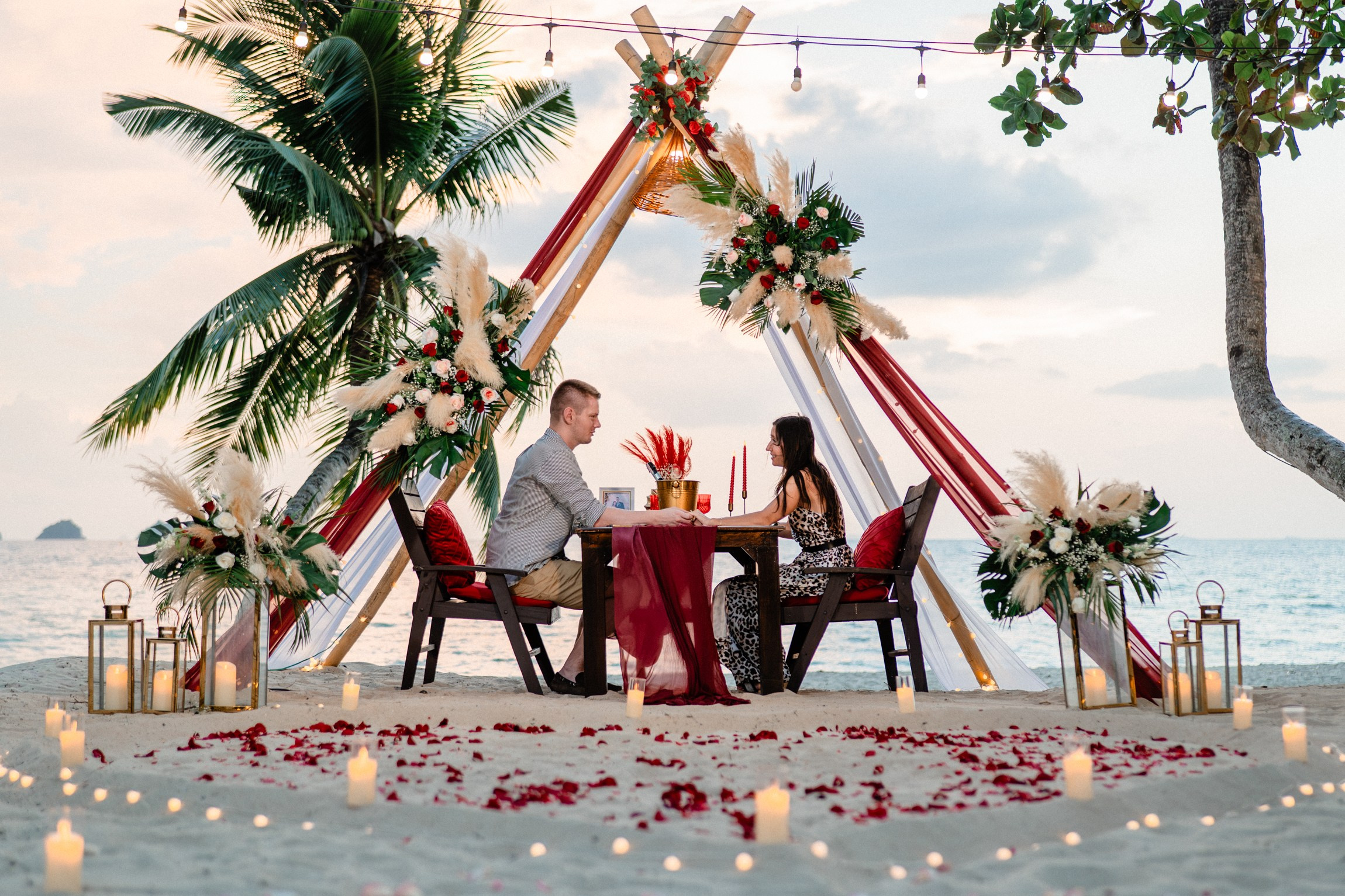 Romantic beach dinner proposal in Koh Samui with a decorated teepee, flowers, candles and an intimate seaside table.