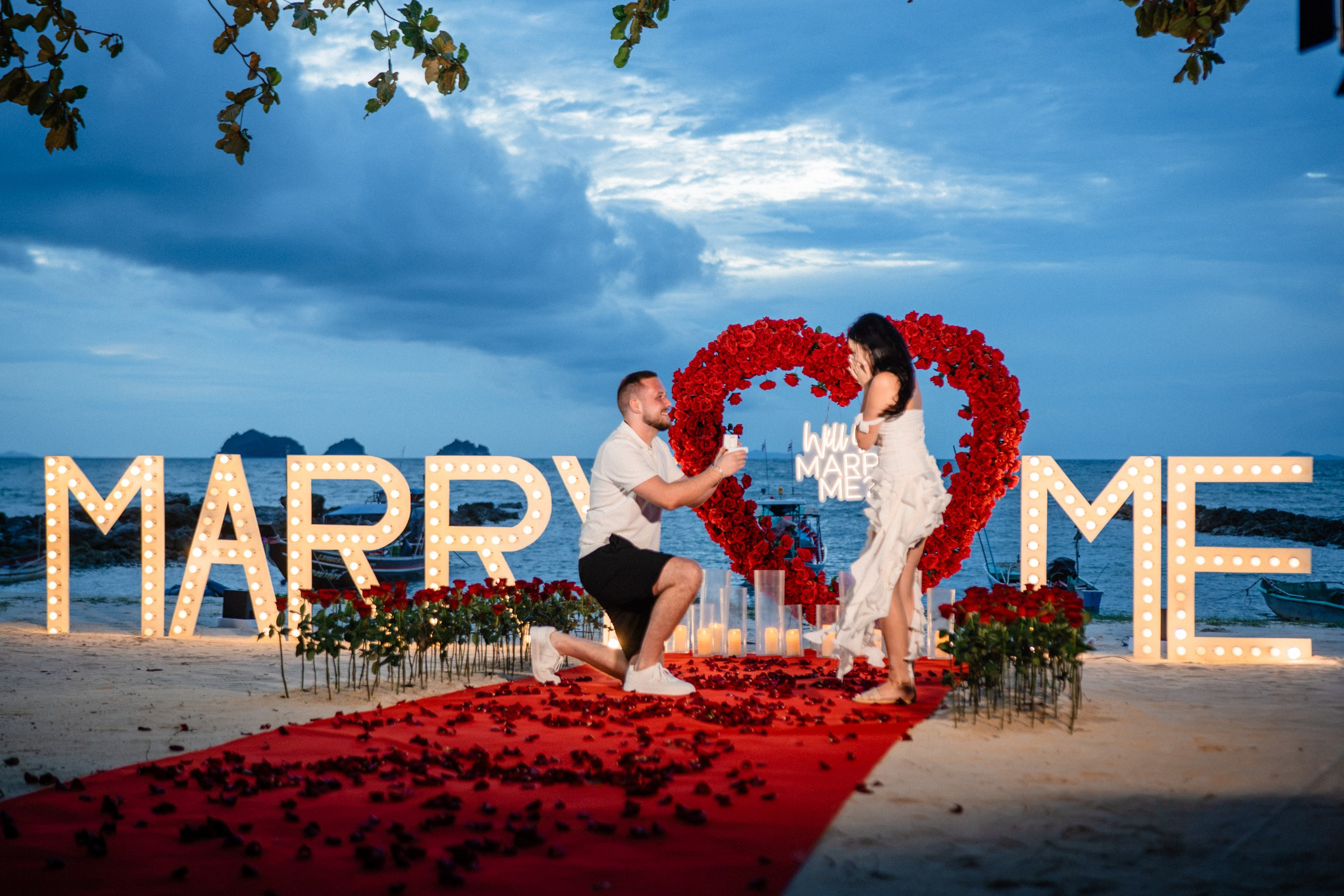 Elegant “Marry Me” beach proposal setup in Koh Samui with rose petals and tropical decor.